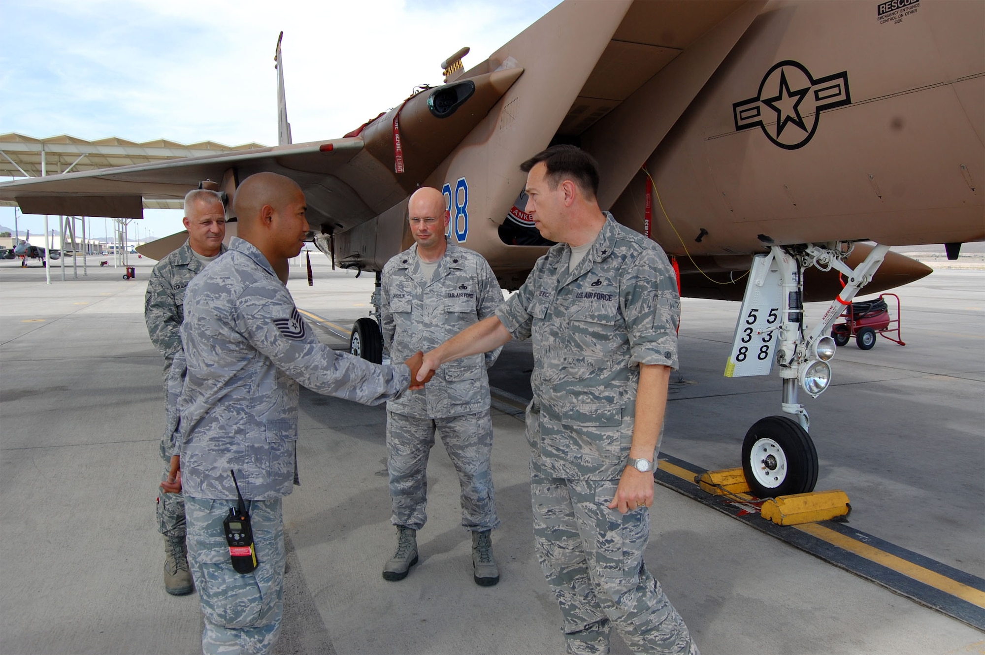 (Left) Tech. Sgt. John Ross Robles, 926th Aircraft Maintenance Squadron weapons loader, receives a coin from Brig. Gen. Gary Blaszkiewicz, Director of Logistics, Headquarters Air Force Reserve Command, Robins Air Force Base, Ga., here June 17. General Blaszkiewicz visited the F-15 Flanker aircraft maintenance unit to talk with reservists integrated with the active duty force at Nellis. Sergeant Robles was identified by his leadership as an outstanding performer. Reservists in the 926th AMXS, like Sergeant Robles, provide additional manpower and expertise to the active duty's 57th Maintenance Group here. 
