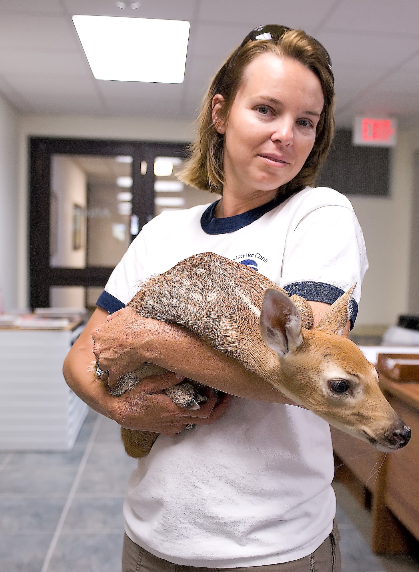 Melody Henderson, Bird/Wildlife Aircraft Strike Hazard ecologist and wildlife manager, holds a fawn she rescued June 9, 2011, at Dover Air Force Base, Del.’s, flightline. Mrs. Henderson is part of an effort by the Air Force to minimize the amount of bird strikes. (U.S. Air Force photo by Steve Kotecki)