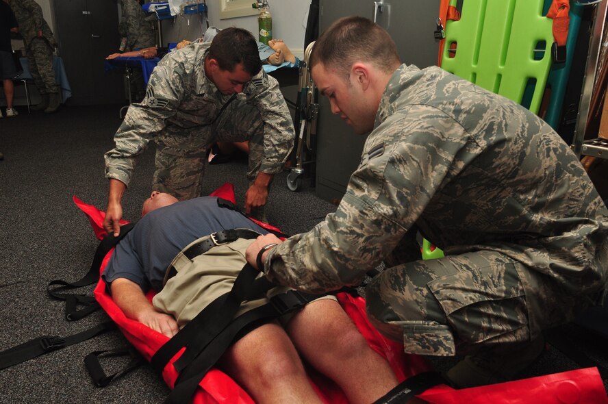 WRIGHT-PATTERSON AIR FORCE BASE, Ohio – Senior Airman Michael Abney  and Airman 1st Class Adam Olsen, 445th Aeromedical Staging Squadron aerospace medical service apprentices,  strap in volunteer Chris Selegue, Tyler Technologies, to a patient litter during a demonstration at the ASTS Medical Education and Training Facility for Employer Appreciation Day June 4. (U.S. Air Force photo/Senior Airman Mikhail Berlin)
