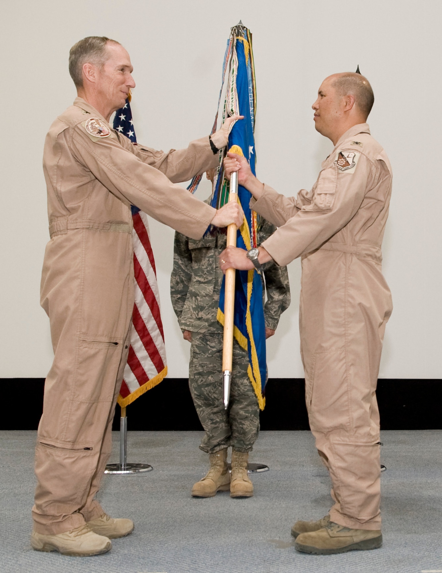 Lt. Gen. Mike Hostage, U.S. Air Forces Central commander, passes the 379th Air Expeditionary Wing guidon to Col. Giovanni K. Tuck at the 379th Air Expeditionary Wing change of command, June 20, at an undisclosed location in Southwest Asia. Colonel Tuck assumed command from Brig. Gen. Randy A. Kee. (U.S. Air Force photo/Senior Airman Paul Labbe)