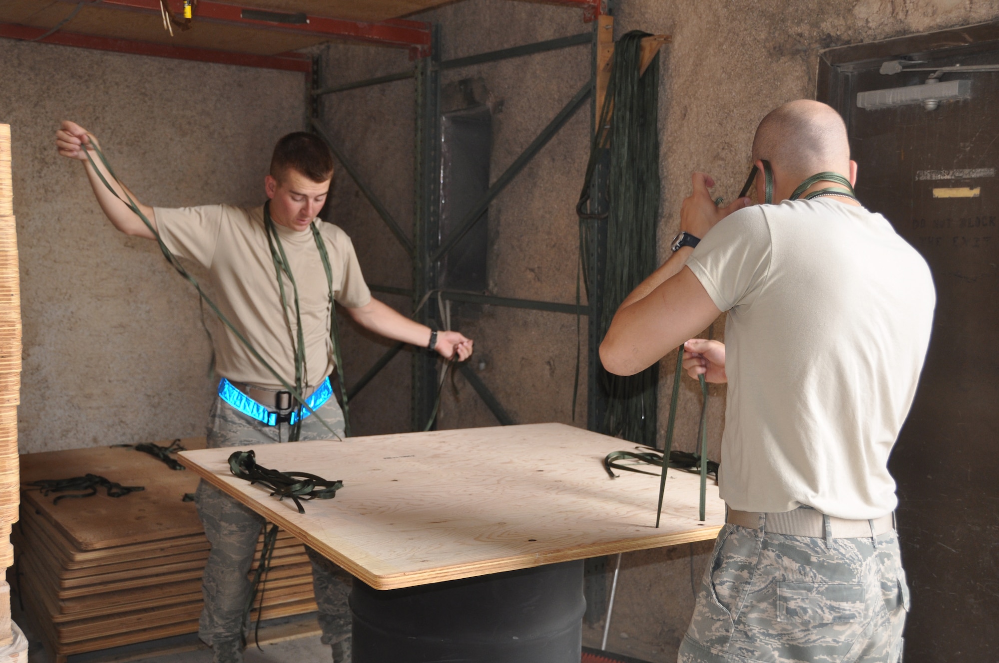 U.S. Air Force Academy Cadet 2nd Class Keegan Peckham and USAFA Cadet 2nd Class Elliot Unseth prepare the pallets for bundles by stringing them with fastening straps while working with the U.S. Army Riggers detachment June 18, 2011, in Southwest Asia. Cadets Peckham and Unseth are taking part in "Deployed Ops", a summer program that sends Academy cadets to deployed locations to follow officers in different career fields and to gain an understanding of career responsibilities. (U.S. Air Force photo/Cadet 1st Class Shaina Thompson)
