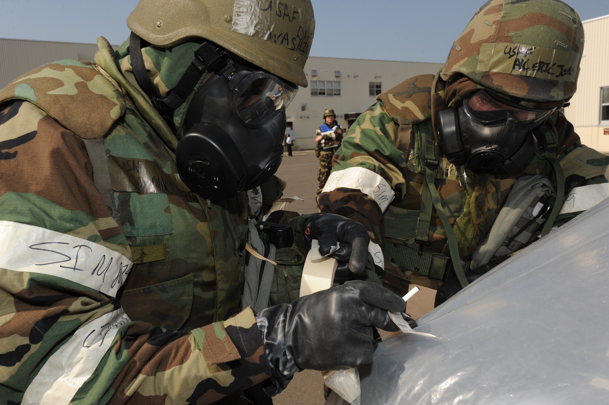 MISAWA AIR BASE, Japan -- Senior Airman David Washington (left), and Airman 1st Class Eric Jones, both from the 35th Civil Engineer Squadron, wear chemical protective ensembles to check for contamination following a simulated attack during a training exercise June 20.  As members of a post attack reconnaisance team, the Airmen are responsible for a number of pre- and post-attack actions designed to protect facilities, equipment and personnel. (U.S. Air Force photo/Staff Sgt. April Quintanilla)