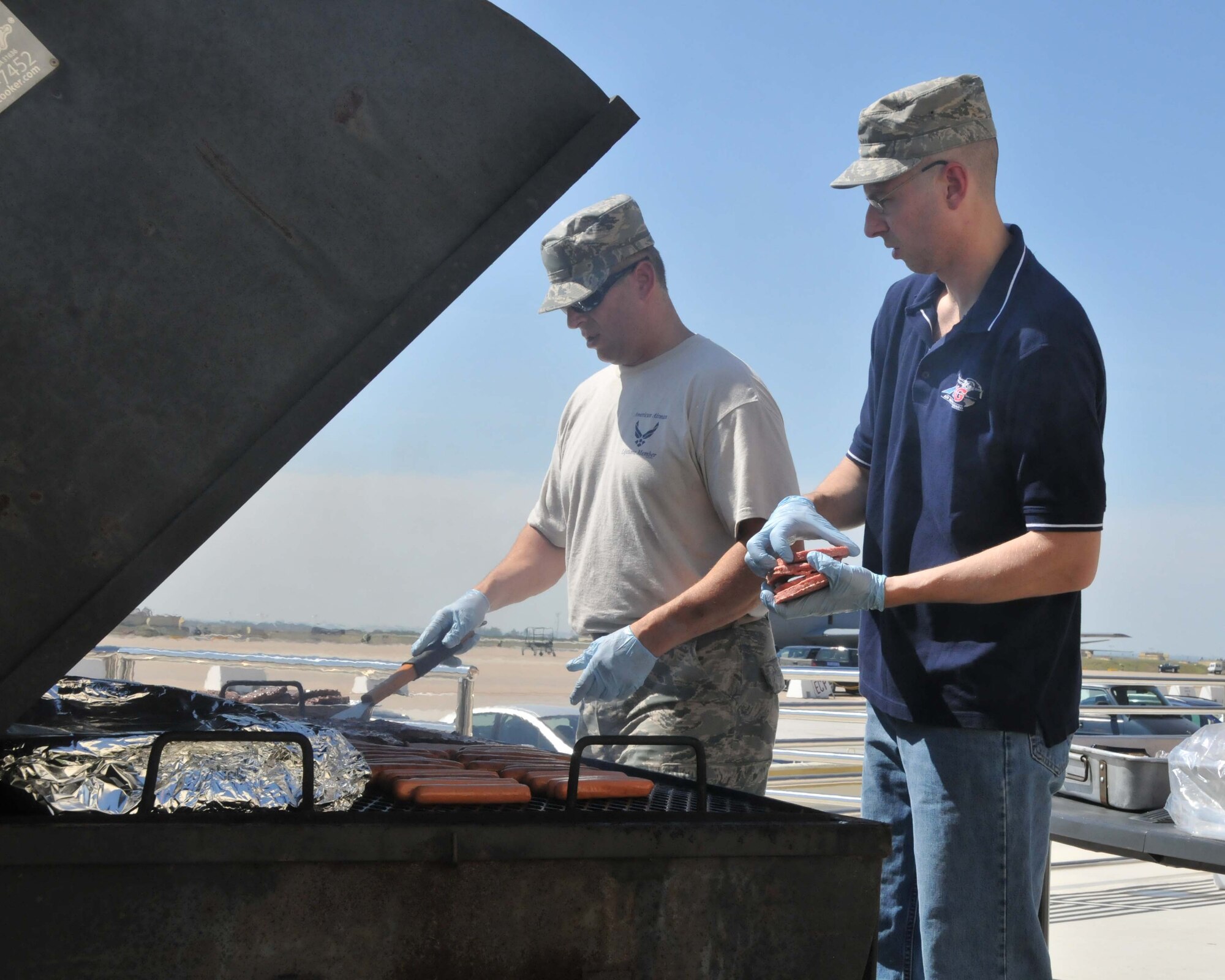 Command Chief Master Sgt. Joseph A. Parlato (left) and 1st Sgt./Senior Master Sgt. Brian C. Boyle, 313th Air Expeditionary Wing prepare hamburgers, hot dogs, and baked beans for esprit-de-corps builder "burger burn" on June 16, 2011 in Western Europe. (U.S. Air Force Photo/Capt John P. Capra)