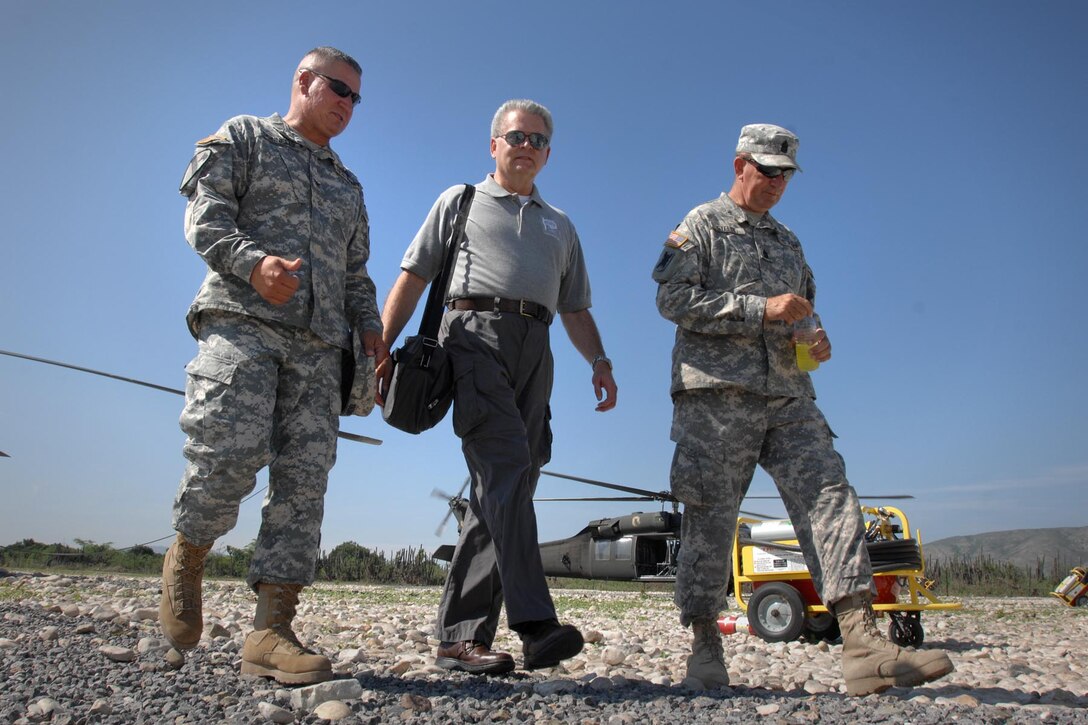Army Col. Kenneth Donnelly, left, and Command Sgt. Maj. Homer Stelly, right, escort Mark Stansberry, chairman of the board of directors of People to People International. The group, along with Operation International Children donated 2,500 school supply kits in the Artibonite department of Haiti, June 16, 2011. The supplies were delivered by the troops of Task Force Bon Voizen, a U.S. Southern Command-sponsored joint foreign humanitarian exercise under the command of the Louisiana National Guard. DOD photo by Fred W. Baker III