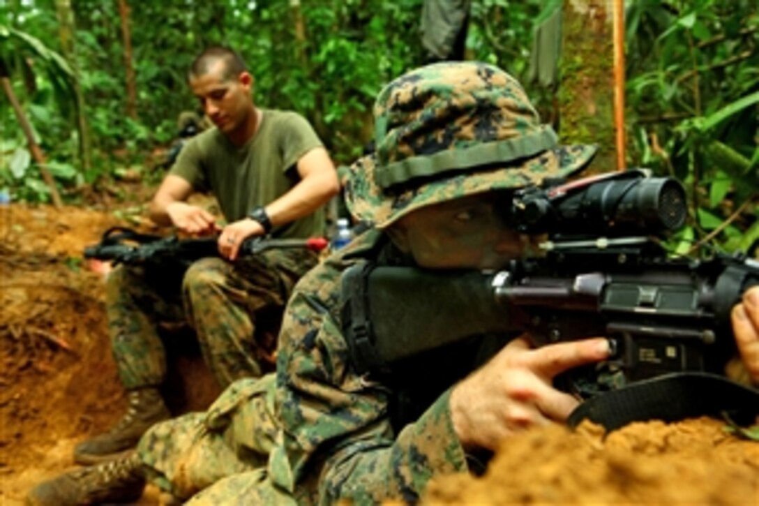 U.S. Marine Corps Lance Cpl. Michael Reed (right), assigned to 2nd Squad, 2nd Platoon, Landing Force Company, provides security with an M16A4 rifle while Lance Cpl. Jesus Puga cleans his weapon during Cooperation Afloat Readiness and Training (CARAT) Malaysia 2011 in Terengganu, Malaysia, on June 11, 2011.  CARAT is a series of bilateral exercises held annually in Southeast Asia to strengthen relationships and enhance force readiness.  