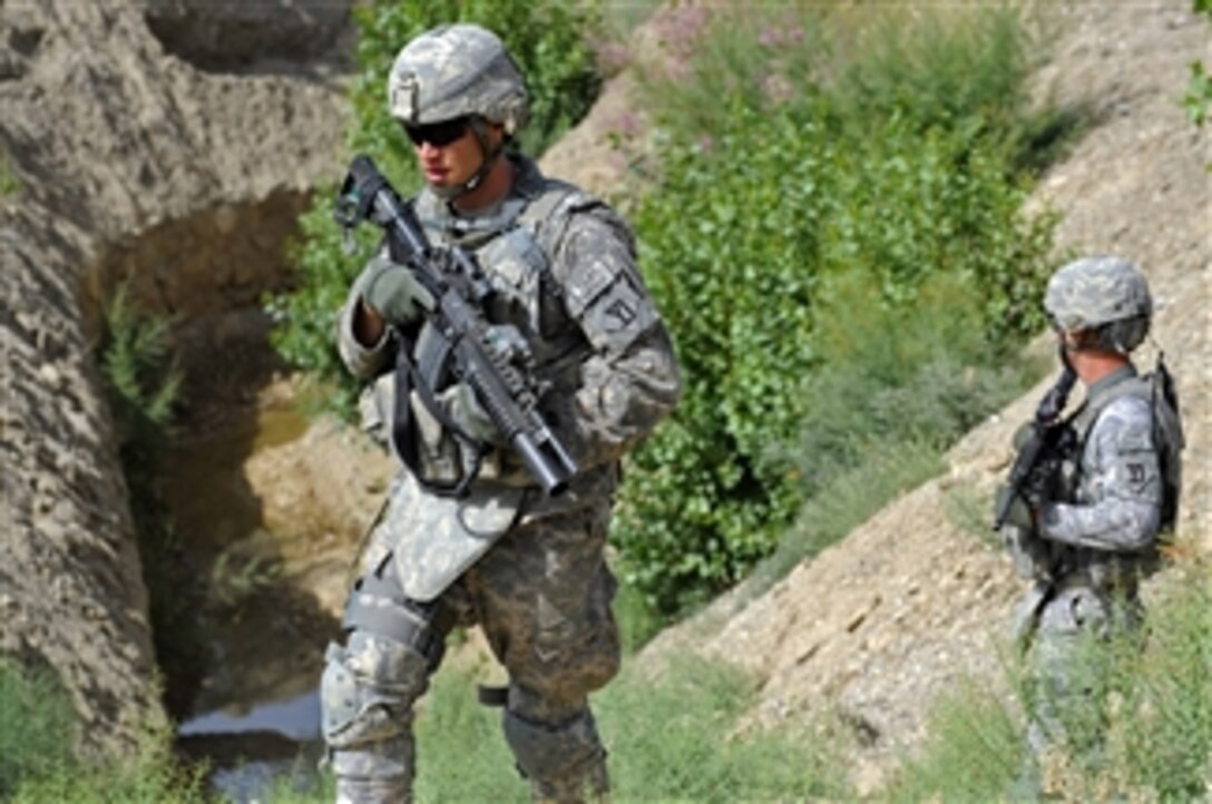 U.S. Army Spc. Daniel Miller (left) and Spc. Daniel Scott, both assigned to the Zabul Provincial Reconstruction Team security force, provide security as members of the team make their way to a canal project site in Zabul province, Afghanistan, on June 14, 2011.  