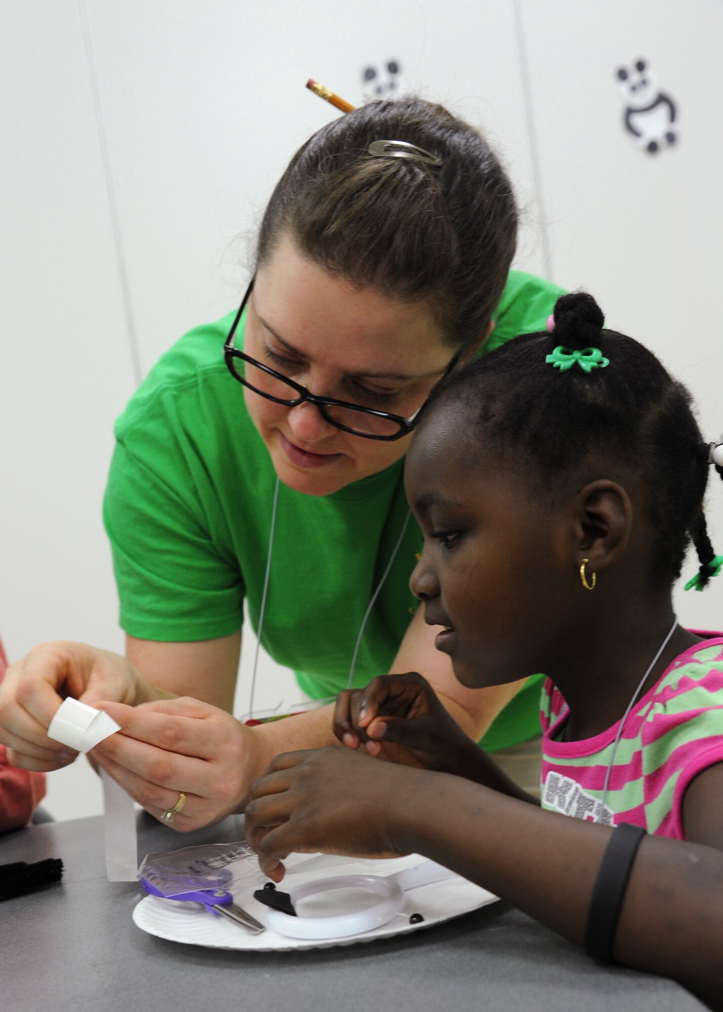YOKOTA AIR BASE, Japan -- Tana Caballero, crafts and missions crew leader, assists Jazmin Fitzpatrick, 6, assemble a panda toy during a vacation bible school arts and crafts lesson June 21, 2011, Yokota Air Base, Japan. The annual weeklong event features bible lessons and activities in a joint effort among the different religious communities at the base chapel. (U.S. Air Force photo/Senior Airman Andrea Salazar)