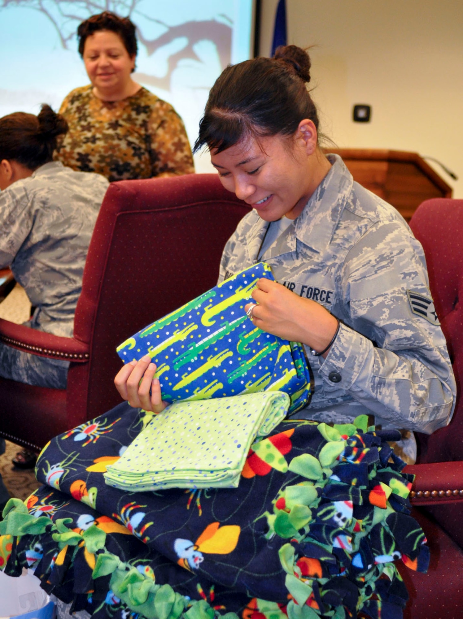 Senior Airman Ashley Carandang, 4th Combat Camera Squadron, sorts through the baby blankets she received at the Bundles for Babies Class at March Air Reserve Base, Calif., June 7, 2011. Bundles for Babies is an Air Force Aid Society sponsored course that helps expectant parents be prepared for the costs of raising a child. In the background, Airman and Family Readiness Center director, Valerie Fioretta, registers participants for the course.(U.S. Air Force photo/Megan Just)