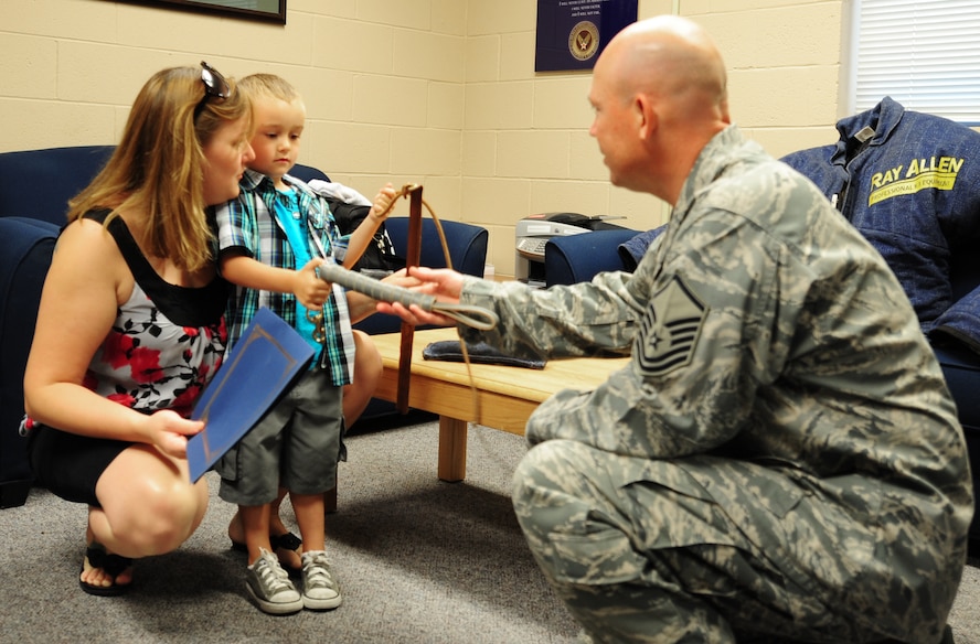 U. S. Air Force Master Sgt. Jamie Morris, 820th Combat Operations Squadron superintendent, presents Charles Long III with a dog leash at Moody Air Force Base, Ga., June 17, 2011. The 820th COS also presented Charles with gifts in remembrance of his father, Staff Sgt. Charles Long II, and coordinated for him to watch a demonstration of the canine obstacle course.   (U.S. Air Force photo by Senior Airman Stephanie Mancha/Released)