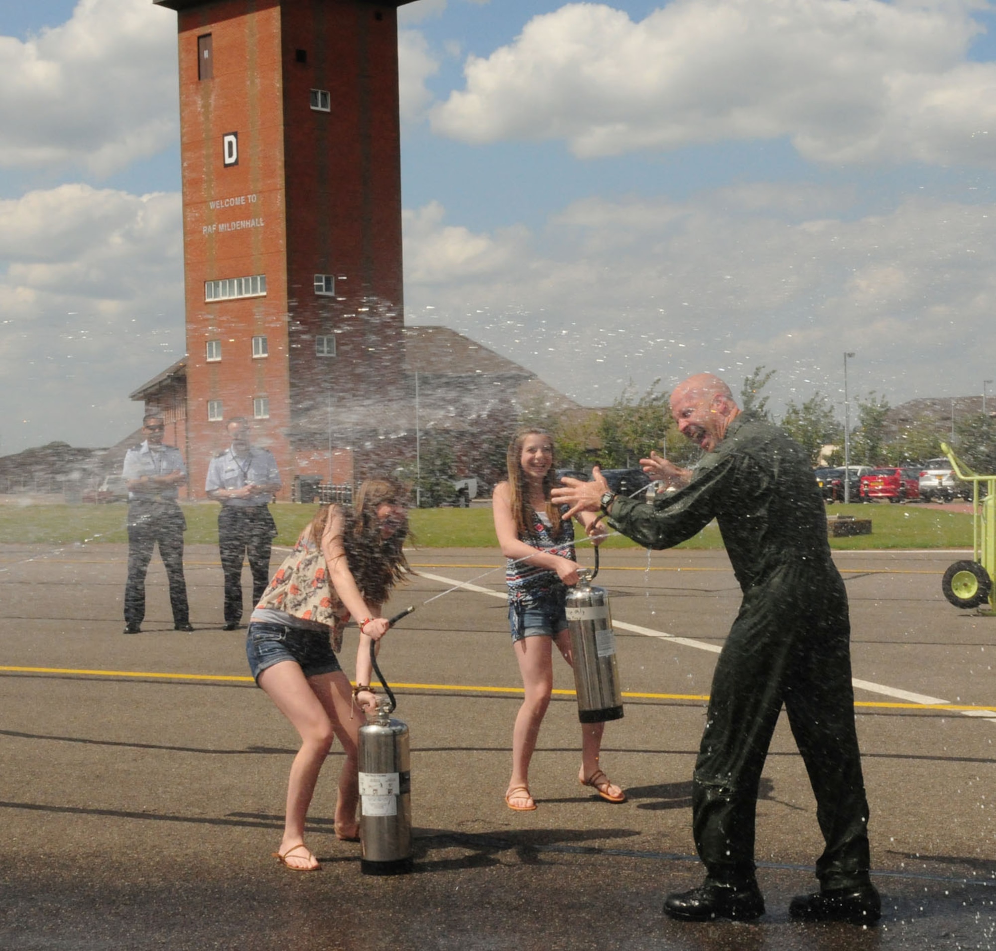 RAF MILDENHALL, England - Col. Chad Manske, 100th Air Refueling Wing commander, gets soaked by Madison, 14, and Reilly, 12, two of his three daughters, in the traditional manner after his final flight here June 20, 2011. The colonel's third daughter, Taylor, 16, and wife Stacey, were also on hand to hose him down. (U.S. Air Force photo/Karen Abeyasekere)