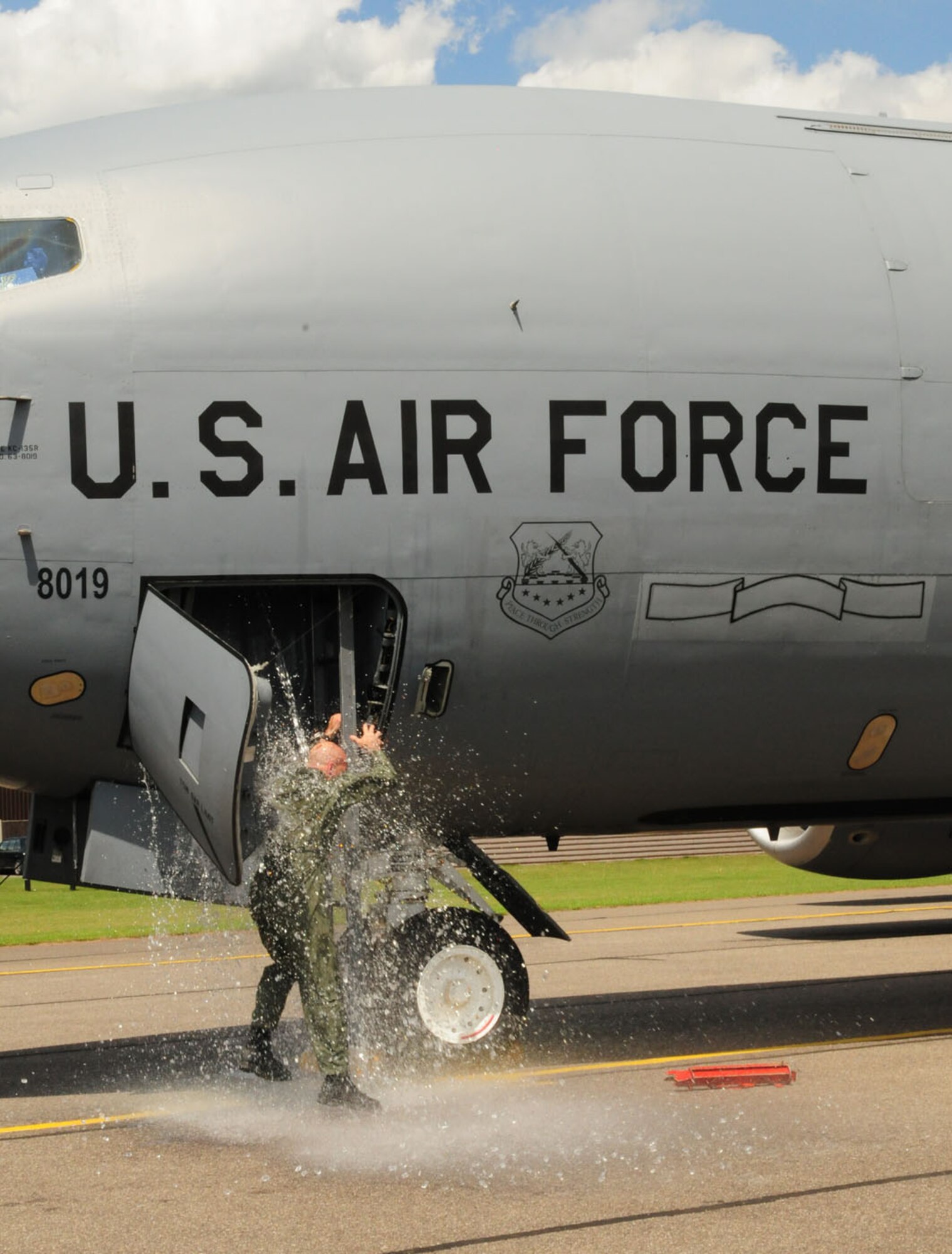 RAF MILDENHALL, England -- Col. Chad Manske, 100th Air Refueling Wing commander, gets soaked as his aircrew tips water and ice cubes over him as he descends from the jet after his final flight here June 20, 2011. Already soaked, Colonel Manske then got hosed down by his wife, Stacey, and daughters, Taylor, 16, Madison, 14, and Reilly, 12, courtesy of the 100th Civil Engineer Squadron Fire Department. (U.S. Air Force photo/Karen Abeyasekere)