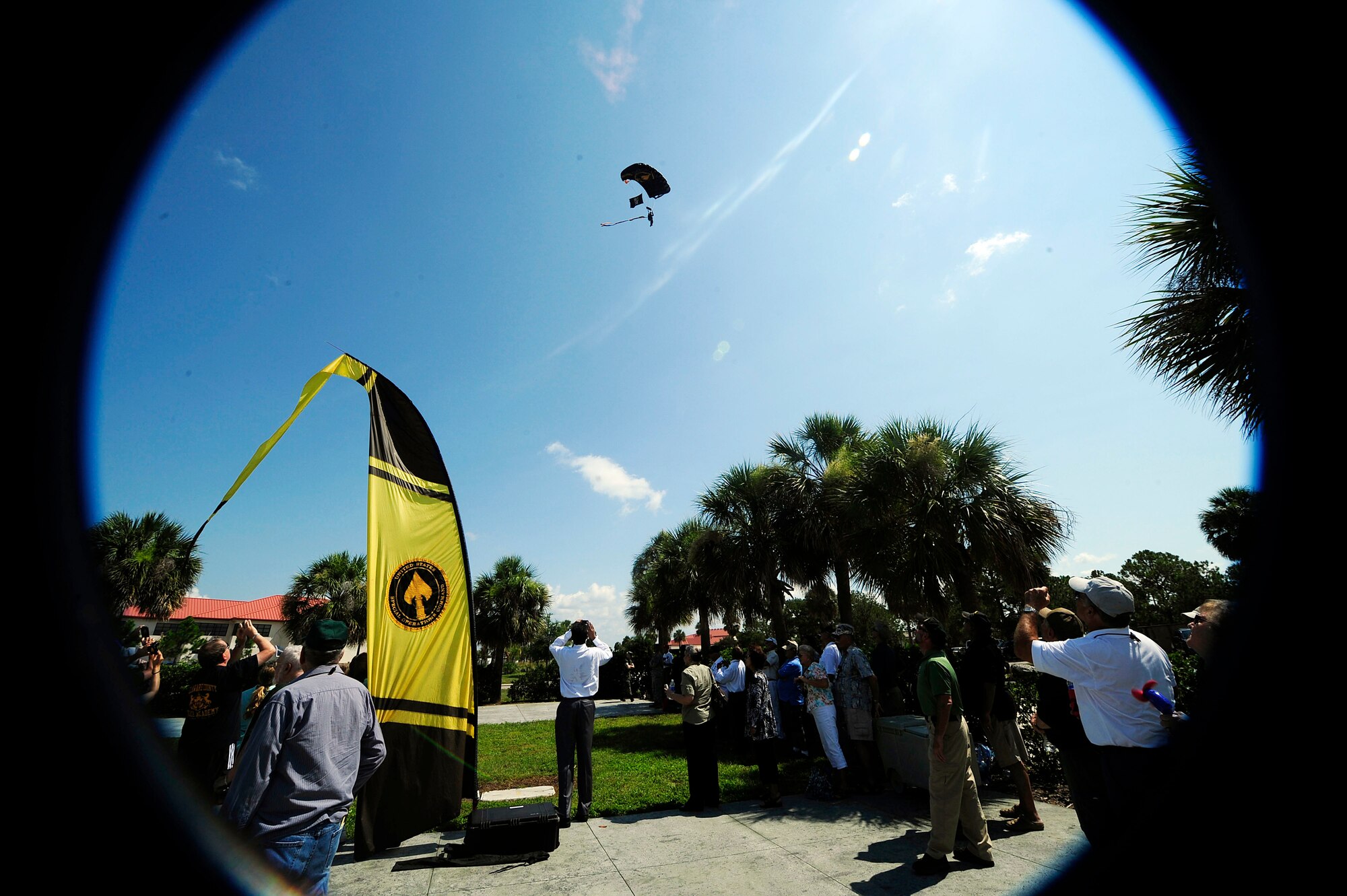 Attendees of the1st Special Forces Group reunion watch as retired U.S. Army Sgt. Maj.  Russ McDaniel, U.S. Special Operations Command Parachute team member, parachutes in with the POW/MIA flag to present to Isaac "Ike" Camacho, former Vietnam POW, at MacDill Air Force Base, June 20, 2011. The memorial service was part of a five-day reunion of former members of the 1st Special Forces group who was celebrating a tradition that dates back 54 years. (U.S. Air Force photo by Senior Airman Melissa V. Brownstein)