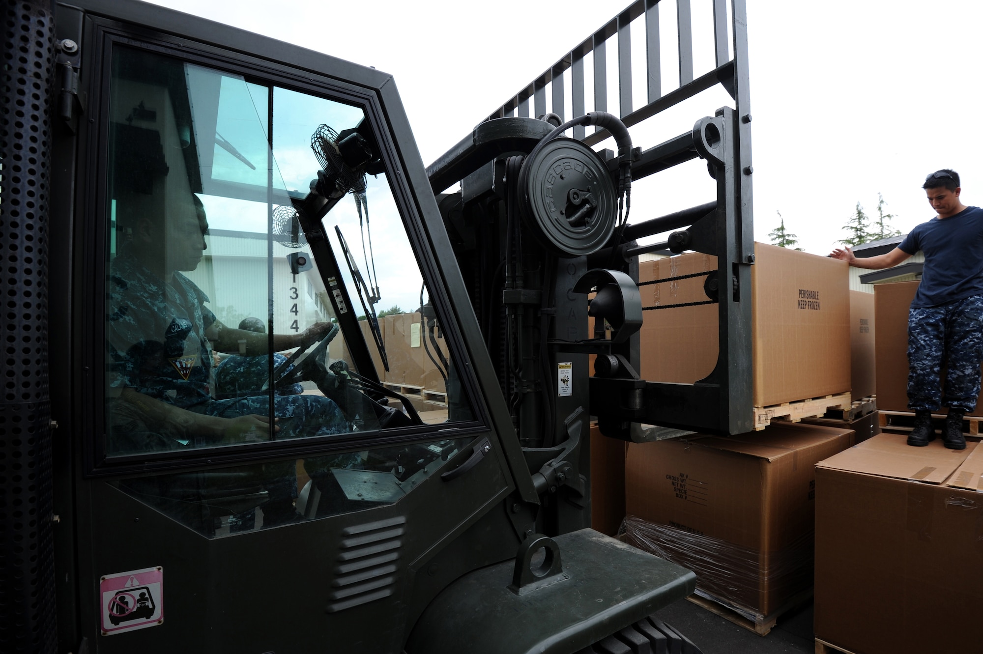 MISAWA AIR BASE, Japan -- U.S. Navy Petty Officer Ronnie Santos guides Petty Officer Edgar Calaguas,  forklift driver, as he unloads humanitarian assistance at a warehouse here June 21.  Members of the Misawa community worked with "The Ron and Don Show," a Seattle-based radio program, to coordinate the collection, shipping and distribution of more than 90,000 pounds of goods from the U.S. to help Japanese orphanages affected by the March 2011 earthquake/tsunami.  (U.S. Air Force photo/ Staff Sgt. April Quintanilla) 