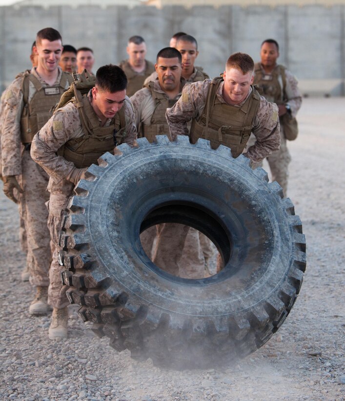 (From left to right) Cpls. Jacob Rooney and Robert Schukar, a Regimental Combat Team 1 field wireman and the RCT-1 administrative non-commissioned officer, heave “Lola” along an exercise circuit here, June 21. Rooney, from Rochester Mills, Mich.; Schukar, from Snohomish, Wash.; and nine other students here labored with Lola, a 200-pound tire, each day during the an 18-day Marine Corps Martial Arts Program Instructor Course. Schukar earned the class’ “Gung-Ho” award for motivation.