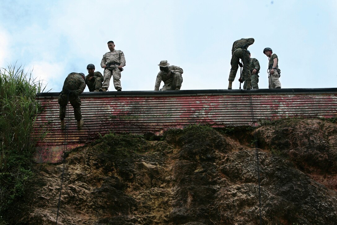 Jungle Warfare Training Center instructors rappel down a wall at Camp Gonzalves June 22. Instructors with Special Operations Training Group, III Marine Expeditionary Force Headquarters Group, III MEF, trained the instructors of JWTC on advanced knot-tying techniques during a nine-day rope-typing instructors course June 21 through July 1.