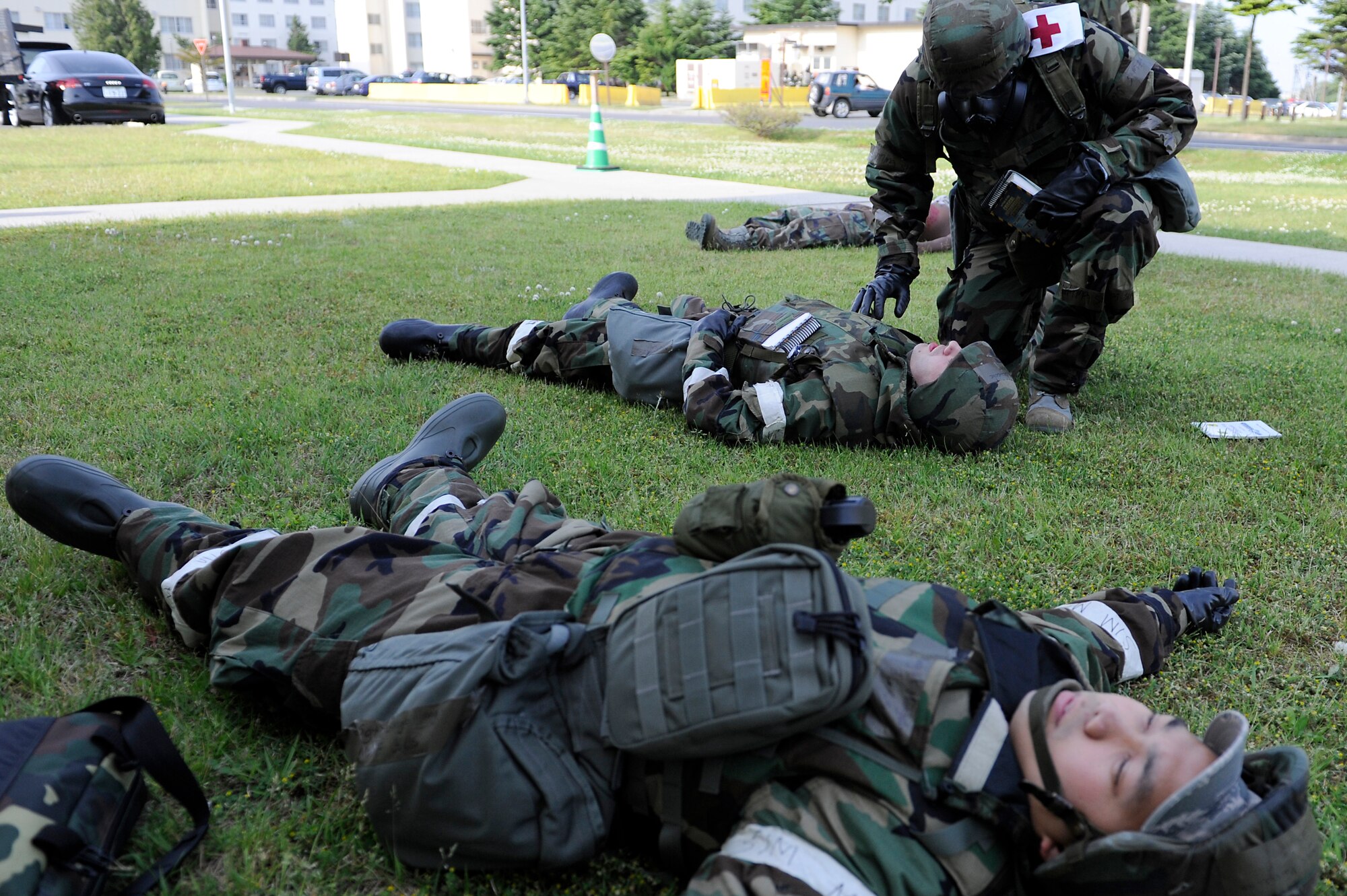MISAWA AIR BASE, Japan -- Staff Sgt. Nathan Henderson, kneeling right, 35th Dental Squadron, assesses victims of a simulated mortar attack during a training exercise June 22. The exercise tested Airmen's ability to survive and operate in a combat environment,  including the application of self-aid and buddy care. (U.S. Air Force photo/Staff Sgt. Marie Brown/Released)