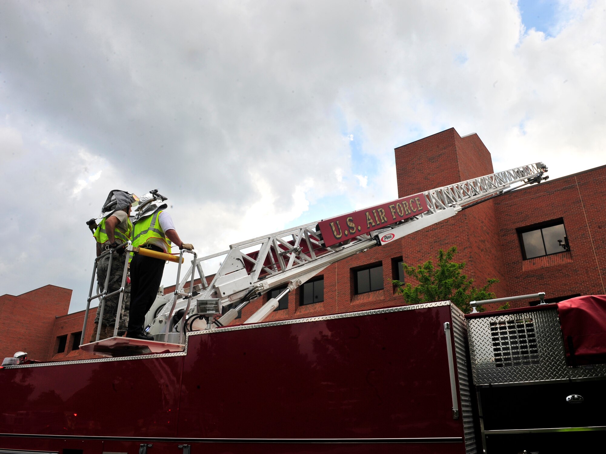 Firefighters from 375th Civil Engineer Squadron raise a turn table ladder over the Air Mobility Command headquarters building June 21, 2011, during a training scenario.  More than 20 firefighters from surrounding off-base fire departments also participated in this scenario. This was the first time a joint fire training scenario was held at the headquarters building.  (United States Air Force photo/ Staff Sgt. Stephenie Wade)