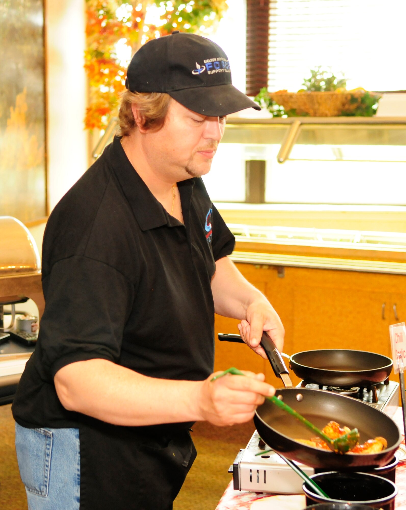 Mike Reardean adds sauce to chicken wings June 15, 2011, Eielson Air Force Base, Alaska.  Mr. Reardean has been working closely with James Clerc, 354th Force Support Squadron kitchen manager, to offer the latest in popular food trends.  Mr. Reardan is assigned to the 354th FSS as lead club assistant.  (U.S. Air Force photo/Airman 1st Class Yash Rojas)