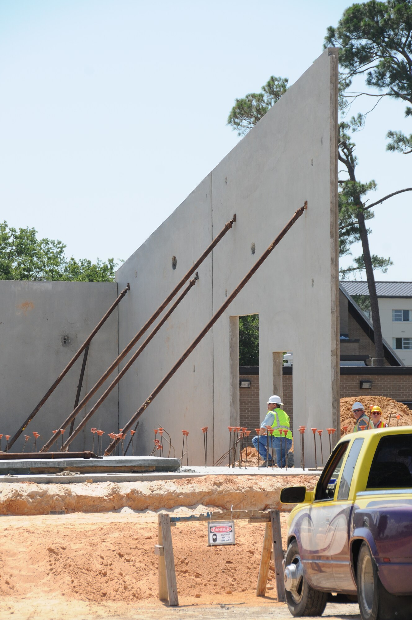 Pre-formed at the site of the firing range, concrete walls are hoisted into place by a crane and supported with temporary braces while construction workers bolt them together.  (U.S. Air Force photo by Kemberly Groue)