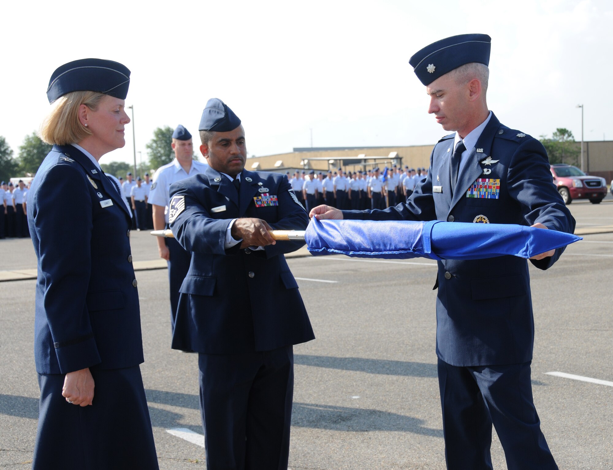 Col. Lynn Connett, left, 81st Training Group commander, looks on as Col. Wall slips a
cover over the 332nd TRS guidon held by Master Sgt. Jimmy Freeman, former 332nd TRS first sergeant now serving as 85th Engineering Installation Squadron first
sergeant. The 81st TRG is awaiting formal approval from Air Staff to deactivate
the squadron.  (U.S. Air Force photo by Kemberly Groue)