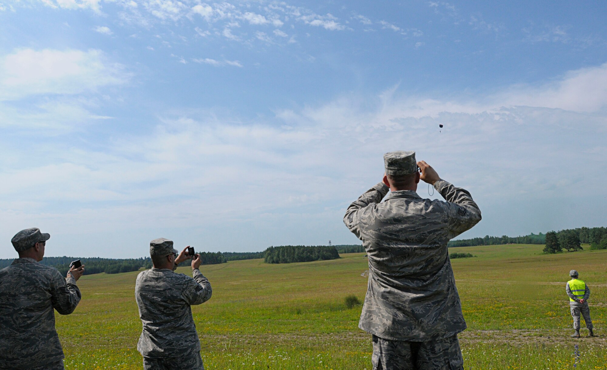U.S. Air Force servicemembers observe a high altitude, low opening "HALO" jump from a C-130J Super Hercules during the opening ceremony for Allied Strike 2011, Grafenwoher Training Area, Germany, June 22, 2011. Allied Strike is Europe's premier Close Air Support exercise, held annually to conduct robust, realistic CAS training that helps build partnership capacity among Allied NATO nations and refine the latest operational CAS tactics. (U.S. Air Force photo by Airman 1st Class Desiree W. Esposito)