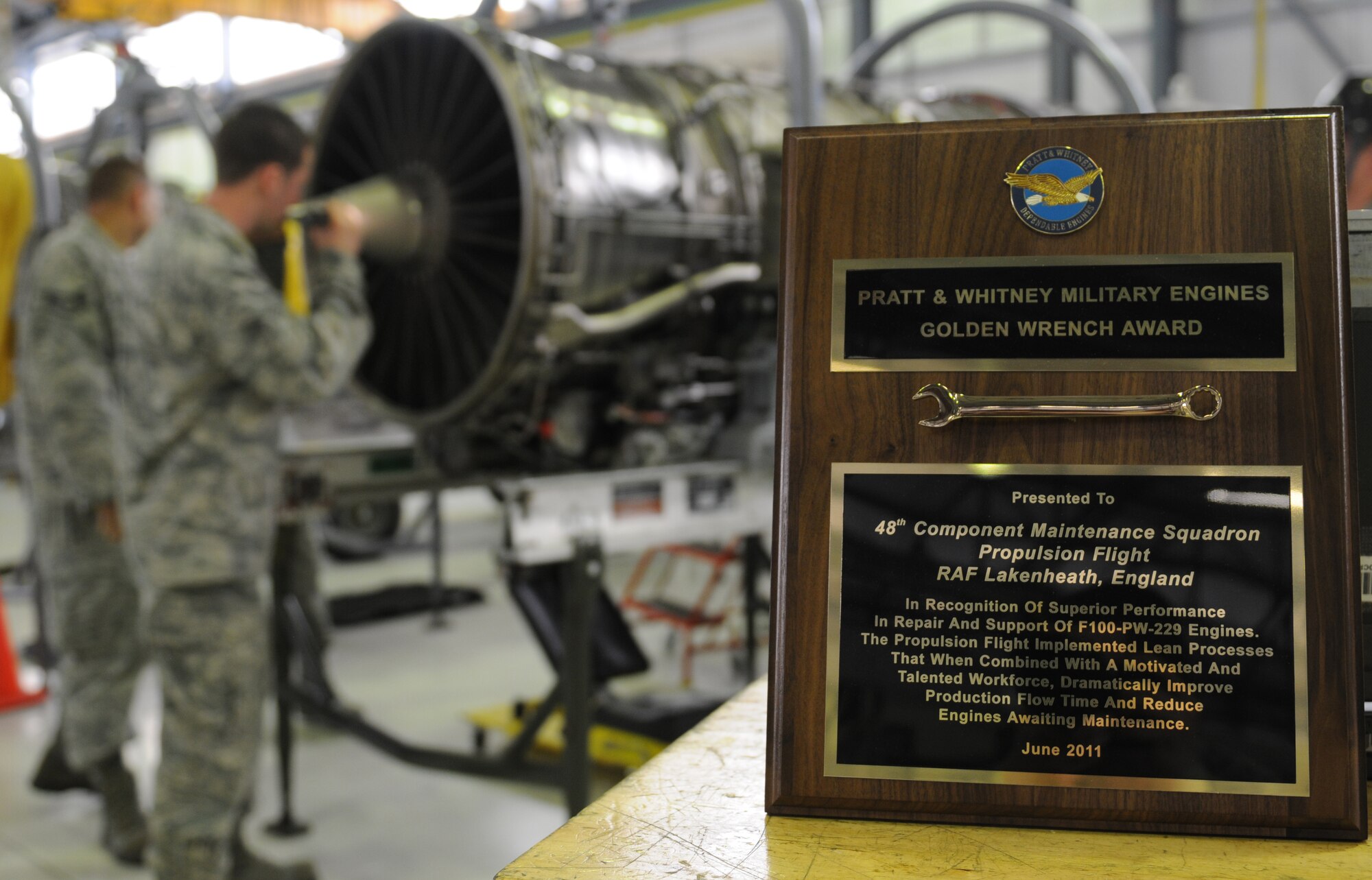 ROYAL AIR FORCE LAKENHEATH, England -- Airmen from the 48th Component Maintenance Squadron Propulsion Flight inspect an F100 engine after being presented the Golden Wrench Award from the Pratt & Whitney aircraft engine company at Building 1225 on June 21, 2011. The flight received the award due to the Airmen's effort in streamlining production of spare engines during the past 18 months.  (U.S. Air Force photo/Airman Cory Payne)