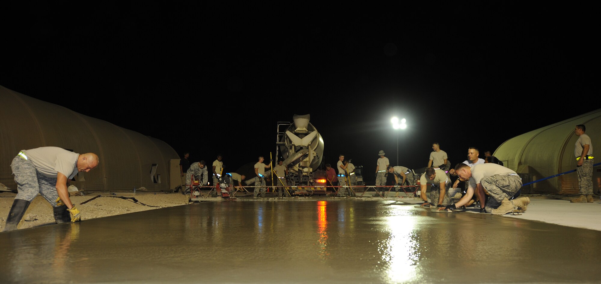 "Dirt Boys" from the 379th Expeditionary Civil Engineer Squadron spread concrete on an area during a project at an air base in Southwest Asia, June 15. (U.S. Air Force photo/Staff Sgt. Liliana Moreno)    