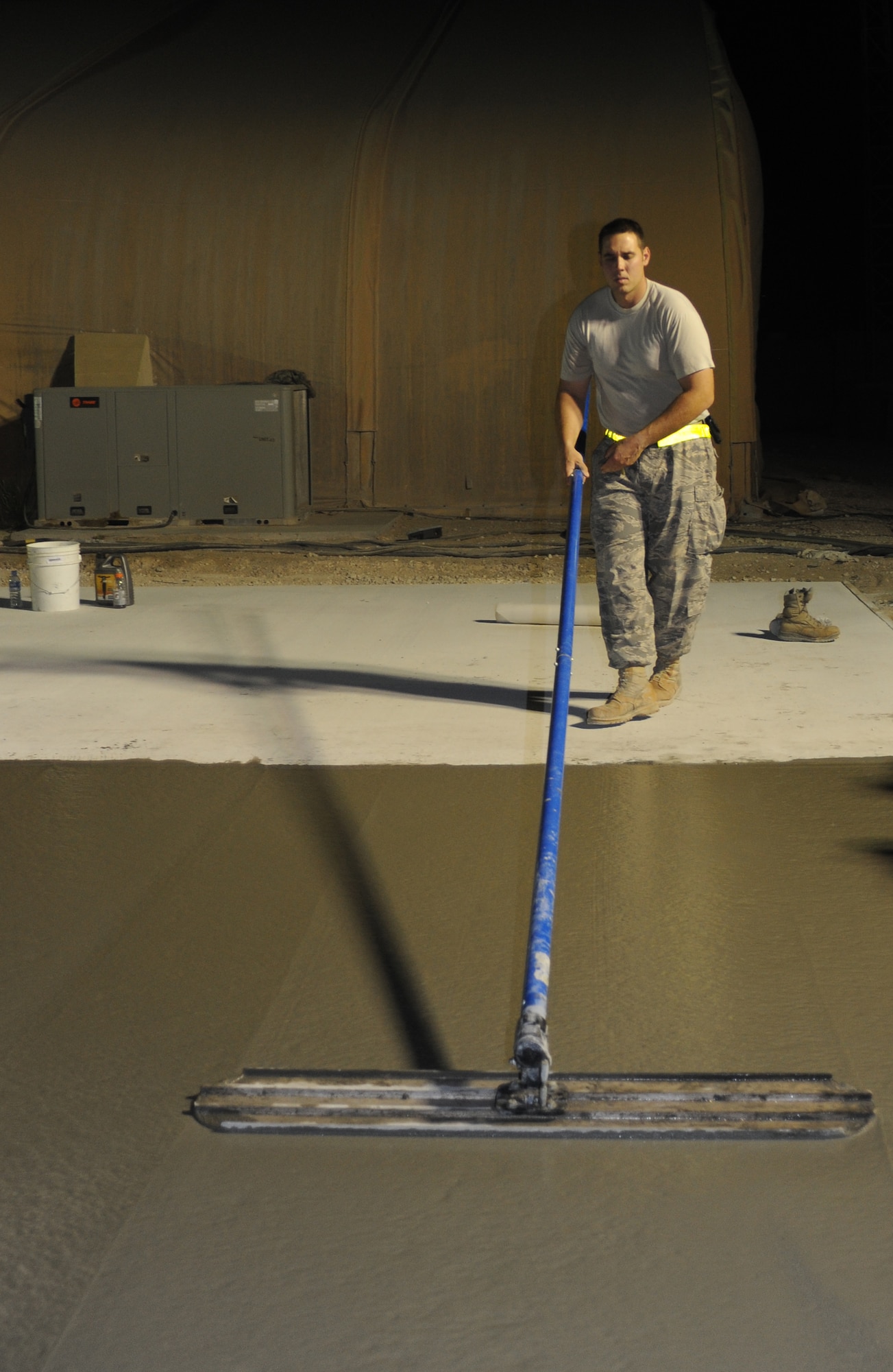 Captain Matthew Joseph, 379th Expeditionary Civil Engineer Squadron, draws a bull float over the fresh concrete during a project at an air base in Southwest Asia, June 15. (U.S. Air Force photo/Staff Sgt. Liliana Moreno)                        