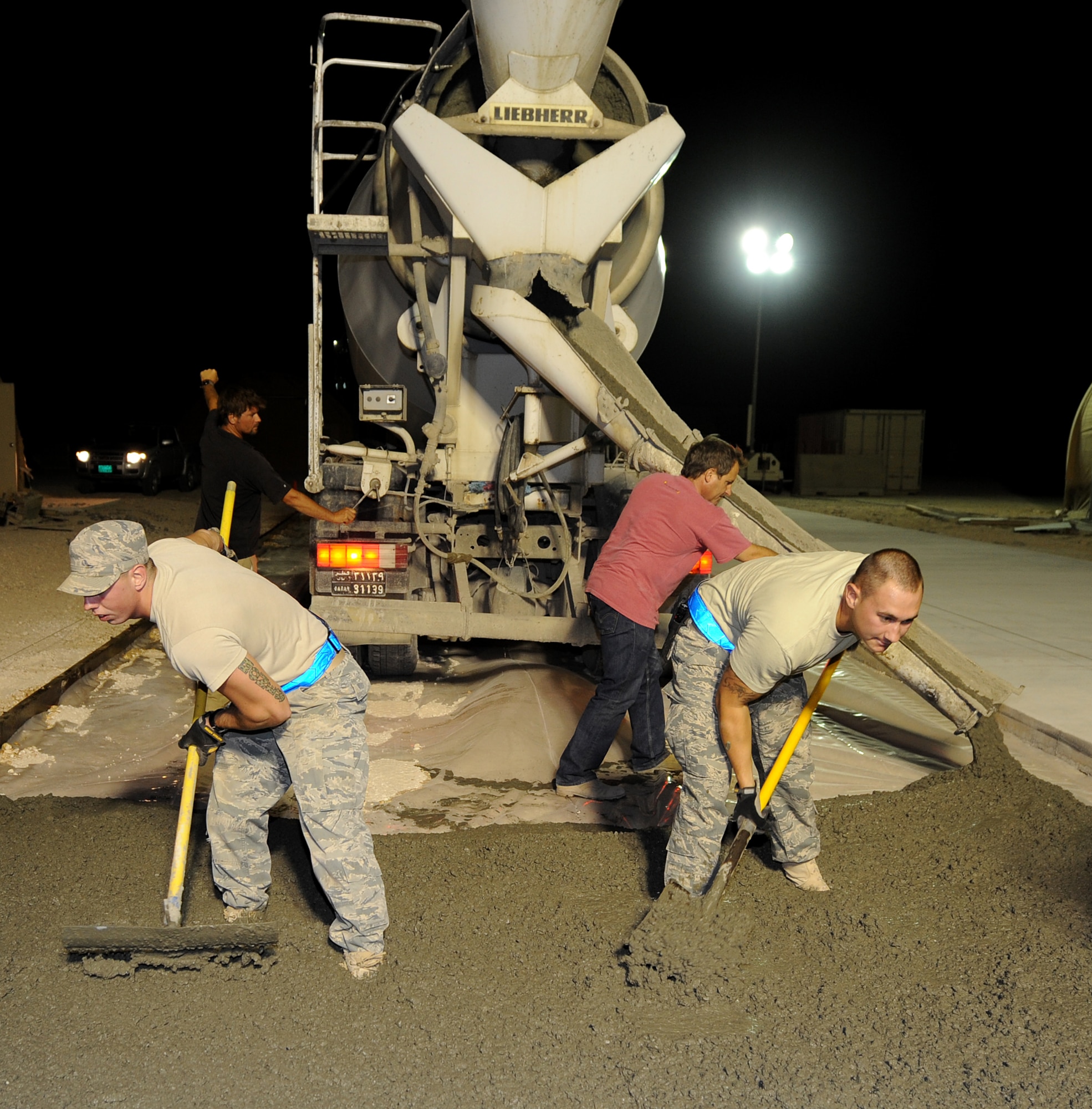 Airman 1st Class Tres Stallard and Staff Sgt. Steven Tharrington, 379th Expeditionary Civil Engineer Squadron "Dirt Boys" spread concrete on an area during a project at an air base in Southwest Asia, June 15. (U.S. Air Force photo/Staff Sgt. Liliana Moreno)              