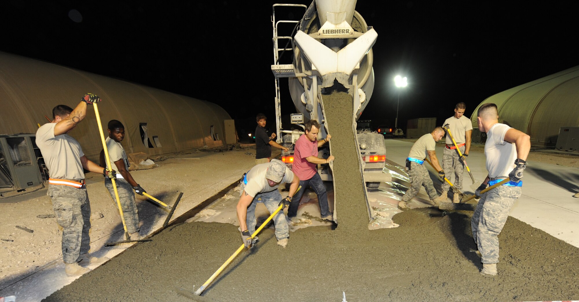 "Dirt Boys" from the 379th Expeditionary Civil Engineer Squadron spread concrete on an area during a project at an air base in Southwest Asia, June 15. (U.S. Air Force photo/Staff Sgt. Liliana Moreno)           
