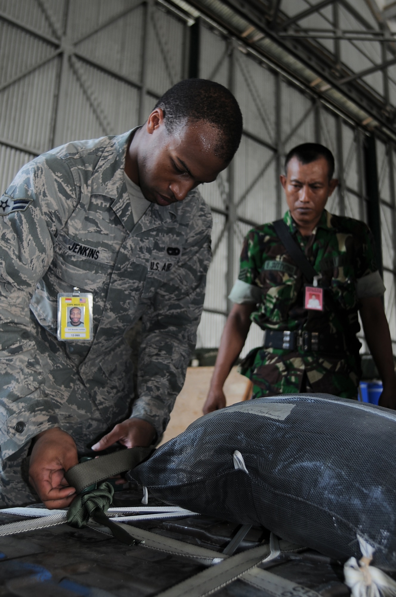 HALIM AIR BASE, Indonesia -- Airman 1st Class Brandon Jenkins, a rigger with the 374th Logistics Readiness Squadron's Combat Mobility Flight demonstrates how to build a Low-Cost, Low-Altitude bundle to a group of Indonesian Air Force and Army riggers during a lesson at Exercise Cope West 11 at Halim Air Base, Indonesia, June 22, 2011. The training seminar, one of several scheduled during the exercise, was designed to encourage information exchange between US and Indonesian forces and promote better interoperability for future combined missions. (U.S. Air Force photo/Capt. Raymond Geoffroy)