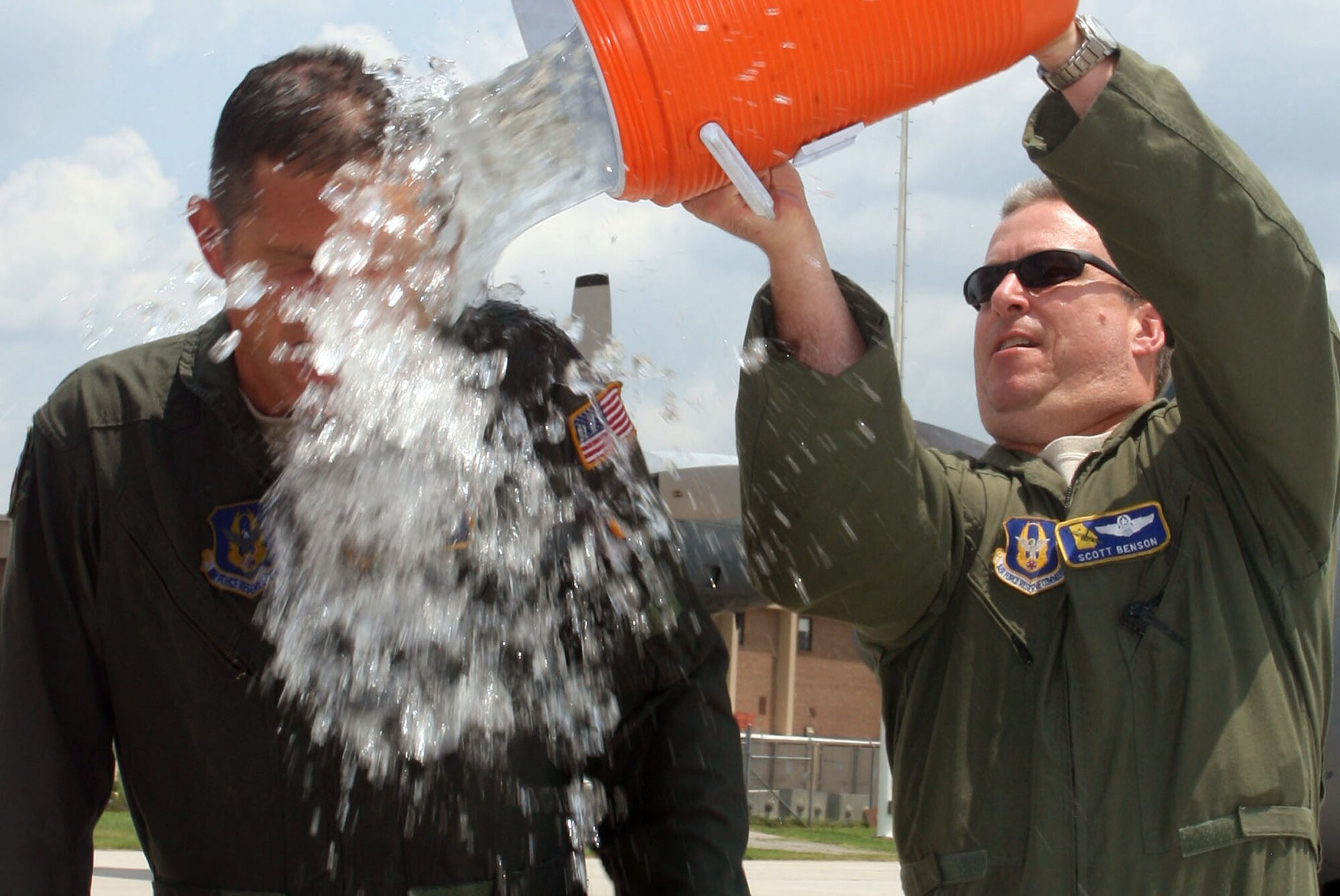 Crew member Lt. Col. Scott Benson from the 700th Airlift Squadron provides the final blast as he empties the ice water bucket over Lt. Col. Soto. (U.S. Air Force Photo/ Don Peek)