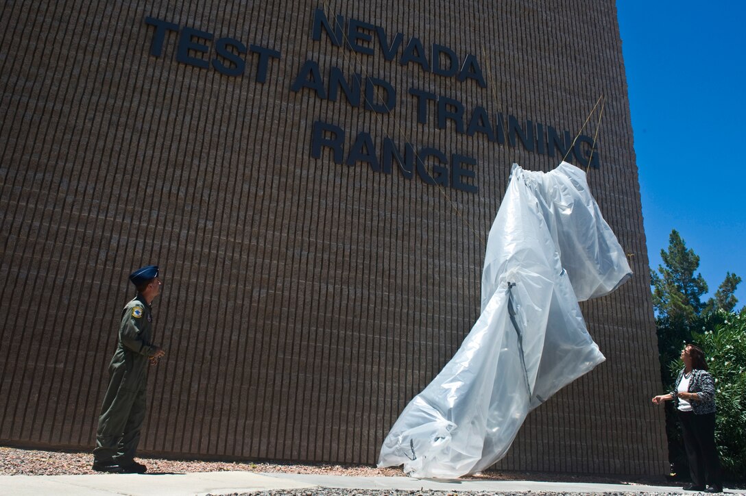 U.S. Air Force Col. Kenneth Thompson, Nevada Test and Training Range commander, and Mrs. Yvonne Gresnick, NTTR deputy director, unveil the new NTTR building sign at Nellis Air Force Base, Nev., after 98th Range Wing was officially re-designated the NTTR June 21, 2011.  Like the 98 RANW, The NTTR will remain a direct reporting unit to the U.S. Air Force Warfare Center and continue to operate, maintain and manage the 2.9-million-acre range (42 percent of the land managed by the U.S. Air Force) and 12,000 square miles of military airspace. More than 1,000 military, civilian and contract personnel are assigned to the organization. (U.S. Air Force photo by Senior Airman Brett Clashman/Released)