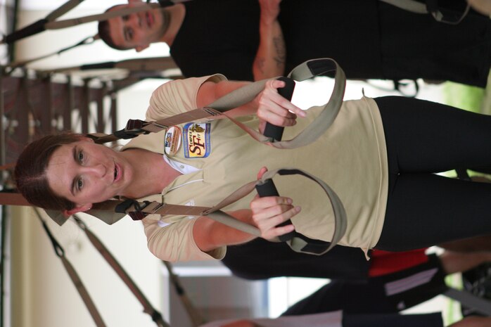 Alma Dickinson, Semper Fit health promotions director, demonstrates an exercise on the Total Resistance Exercise Suspension Trainer for Marines and sailors during the Semper Fit Combat Fitness Course behind the IronWorks Gym here June 23. The course focused on providing noncommissioned officers and above different ways to train junior Marines and sailors.