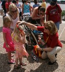 Gloria Pryor of Marine Corps Systems Command's Corporate Communications Directorate gives a child a Marine Corps lanyard during Marine Week St. Louis.