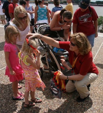 Gloria Pryor of Marine Corps Systems Command's Corporate Communications Directorate gives a child a Marine Corps lanyard during Marine Week St. Louis.