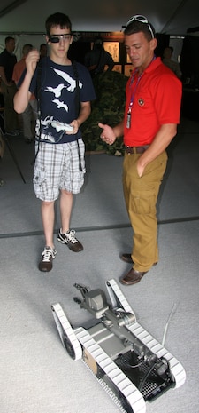 Scott Gatto of the Robotic Systems Joint Program Office  shows a young visitor how to operate one of their many robots during Marine Week St. Louis.