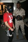 A Marine Week St. Louis visitor tries on an M50 Field Protective Mask with the help of Master Sergeant Eugene Champion of Marine Corps Systems Command's Combat Equipment and Support Systems.