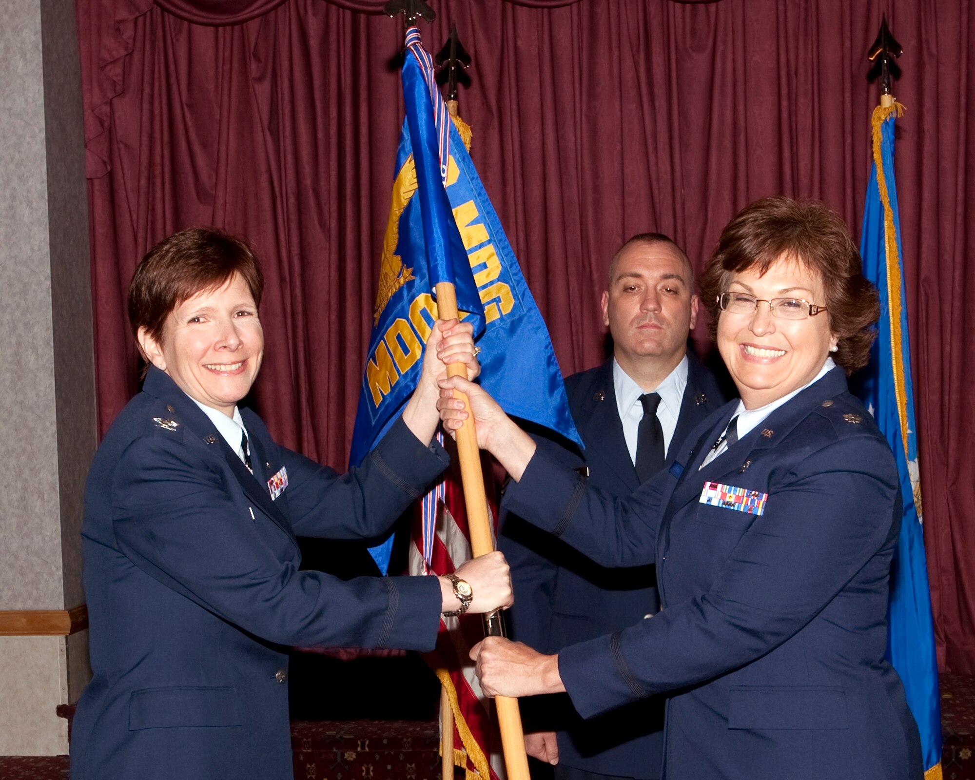 Col. Francesca Vasta-falldorf, 90th Medical Group commander, presents the guidon for the 90th Medical Operations Squadron to Lt. Col. Katherine Spence while Master Sgt. Brian Sartori, 90th MDOS first sergeant, looks on during the 90th MDOS change-of-command ceremony held in the Trail’s End Club June 22. (U.S. Air Force photo by Matt Bilden)