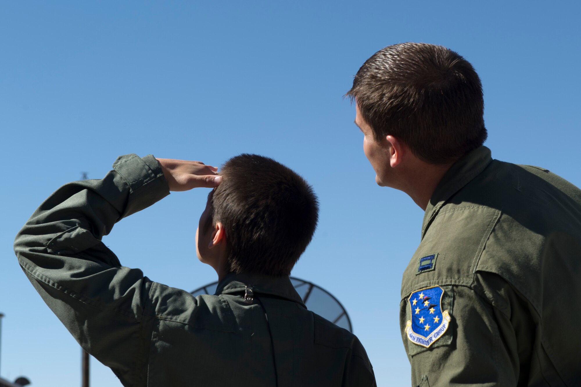 HOLLOMAN AIR FORCE BASE, N.M. -- A.J. Harrison, 16, and Captain Ken Peterson, 301st Fighter Squadron, observe nearby aircraft June 21, 2011, outside the 7th FS. The 301st FS is starting a program which gave A.J., a local youth with spina bifida, an opportunity to be part of their squadron for a day. He was given a mission brief, aircrew flight equipment familiarization, and a pilot’s point of view in an F-22 Raptor’s cockpit. (U.S. Air Force photo by Airman 1st Class Joshua Turner/Released)