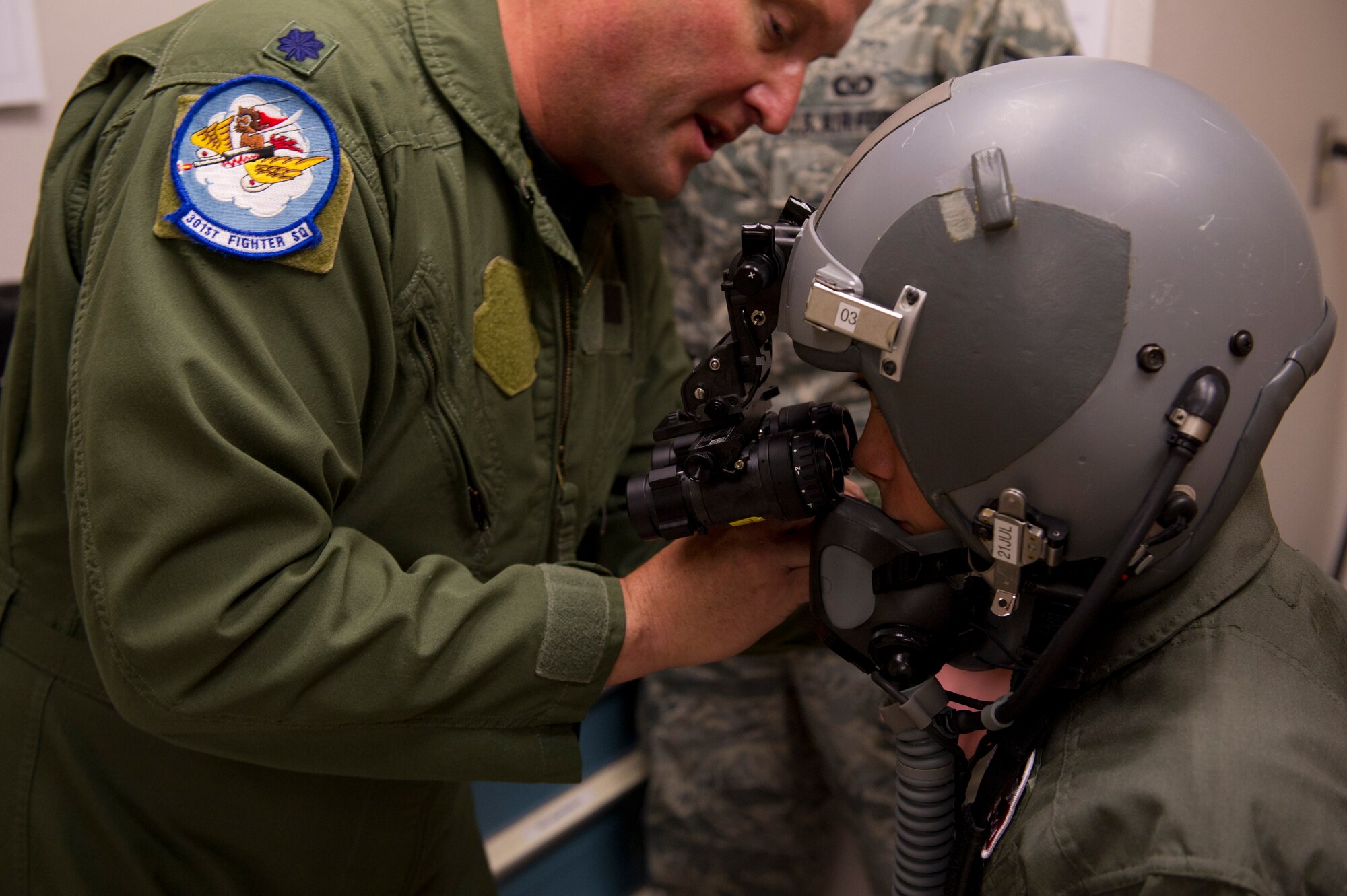 HOLLOMAN AIR FORCE BASE, N.M. -- Lt. Col. Robert Buchanan, 301st Fighter Squadron, attaches night vision goggles on the helmet A.J. Harrison, 16, is wearing, June 21, 2011, during his tour of the 7th Fighter Squadron Aircrew Flight Equipment. A.J., who has spina bifida, was given the opportunity to be a fighter pilot for a day with the 301st FS. He was provided a mission brief, AFE familiarization, and a pilot’s point of view in an F-22 Raptor’s cockpit. (U.S. Air Force photo by Airman 1st Class Joshua Turner/Released)