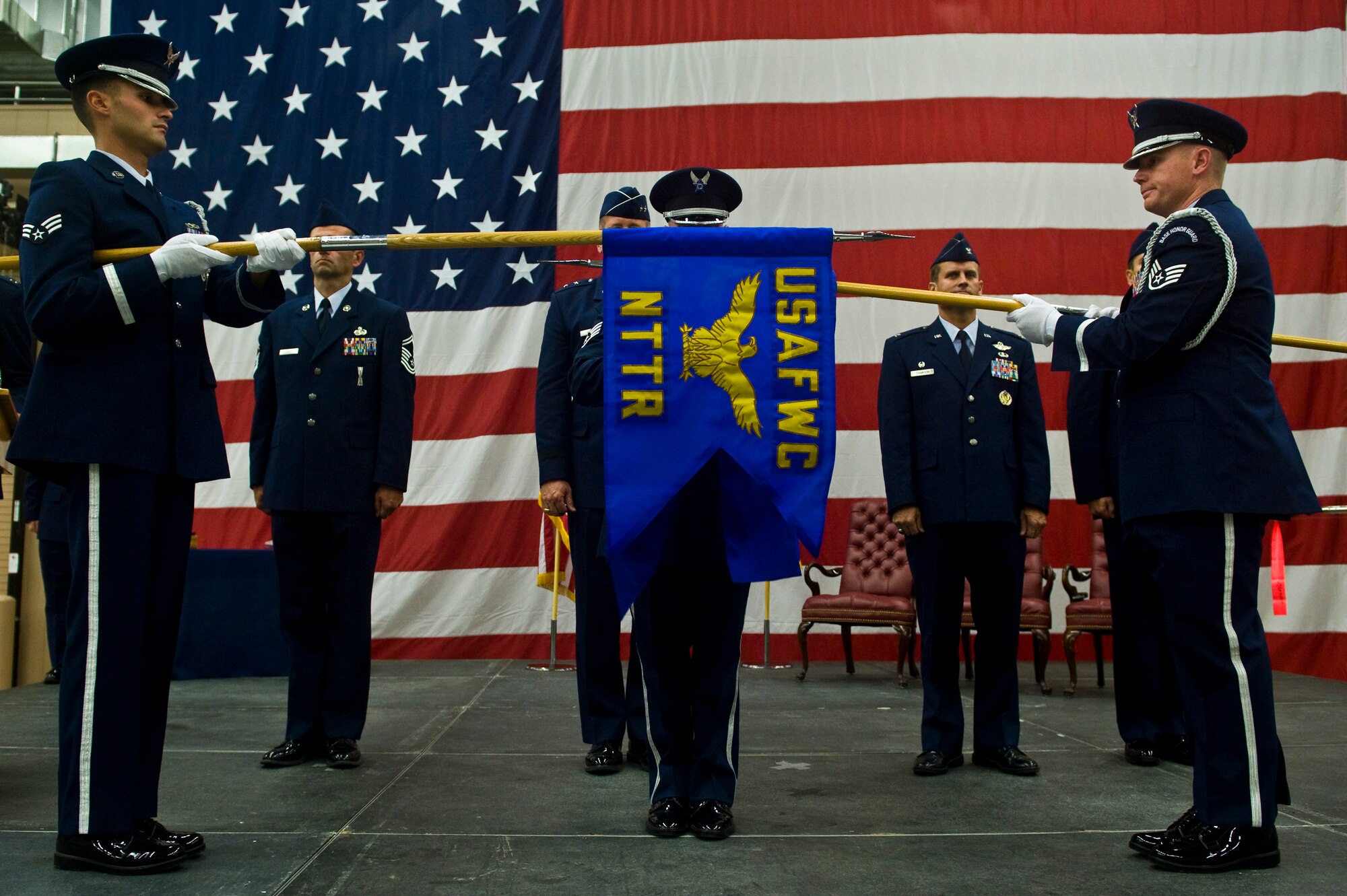 Nellis Air Force Base Honor Guard members unfurl The Nevada Test and Training Range guidon during a ceremony re-designating the 98th Range Wing as the NTTR at Nellis Air Force Base, Nev., June 21, 2011. Col. John Montgomery relinquished command of the 98 RANW and Col. Kenneth Thompson, former defense and air attaché to the U.S. Embassy in Cairo, assumed command of the NTTR during the event. Like the 98 RANW, The NTTR will remain a direct reporting unit to the U.S. Air Force Warfare Center and continue to operate, maintain and manage the 2.9-million-acre range (42 percent of the land managed by the U.S. Air Force) and 12,000 square miles of military airspace. More than 1,000 military, civilian and contract personnel are assigned to the organization. (U.S. Air Force photo by Senior Airman Brett Clashman/Released)