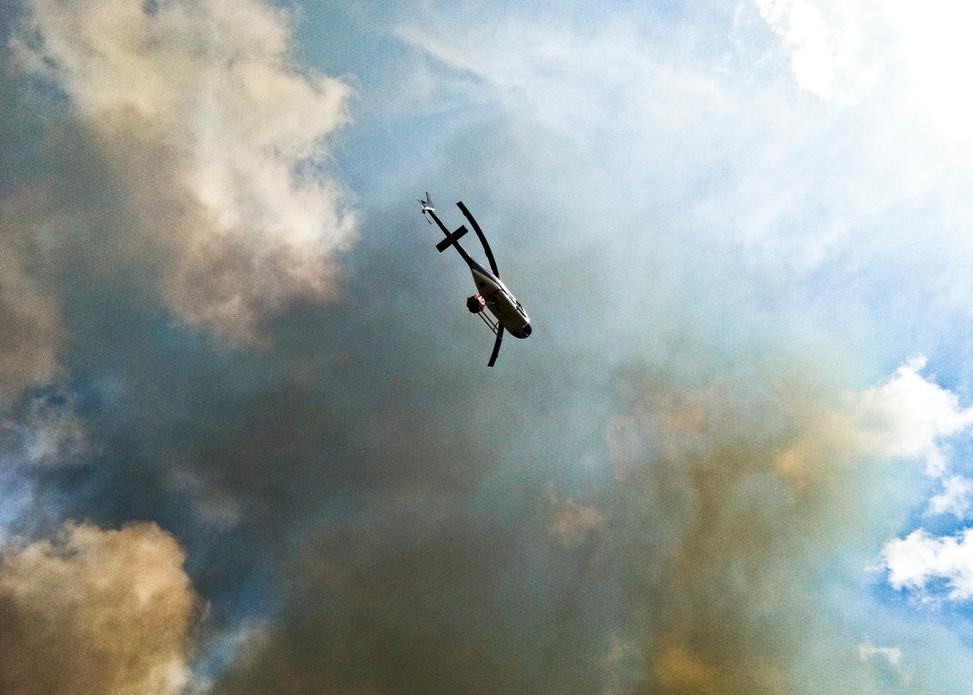 Firefighters from Jackson Guard's fire management section fly aboard a Bell 206B Jet Ranger helicopter to fight the wildfires from the air June 22. The helicopter can carry up to 100 gallons of water in the "Bambi" bucket and place water strategically and safely. The helicopter is contracted to support Eglin's Fire Management Program in both prescribed burning and fire suppression efforts.  The wildfires burned more than 15 acres of forest and threatened homes and businesses, but due to firefighting efforts no structures were damaged.  (U.S. Air Force photo/Roger Kennedy)