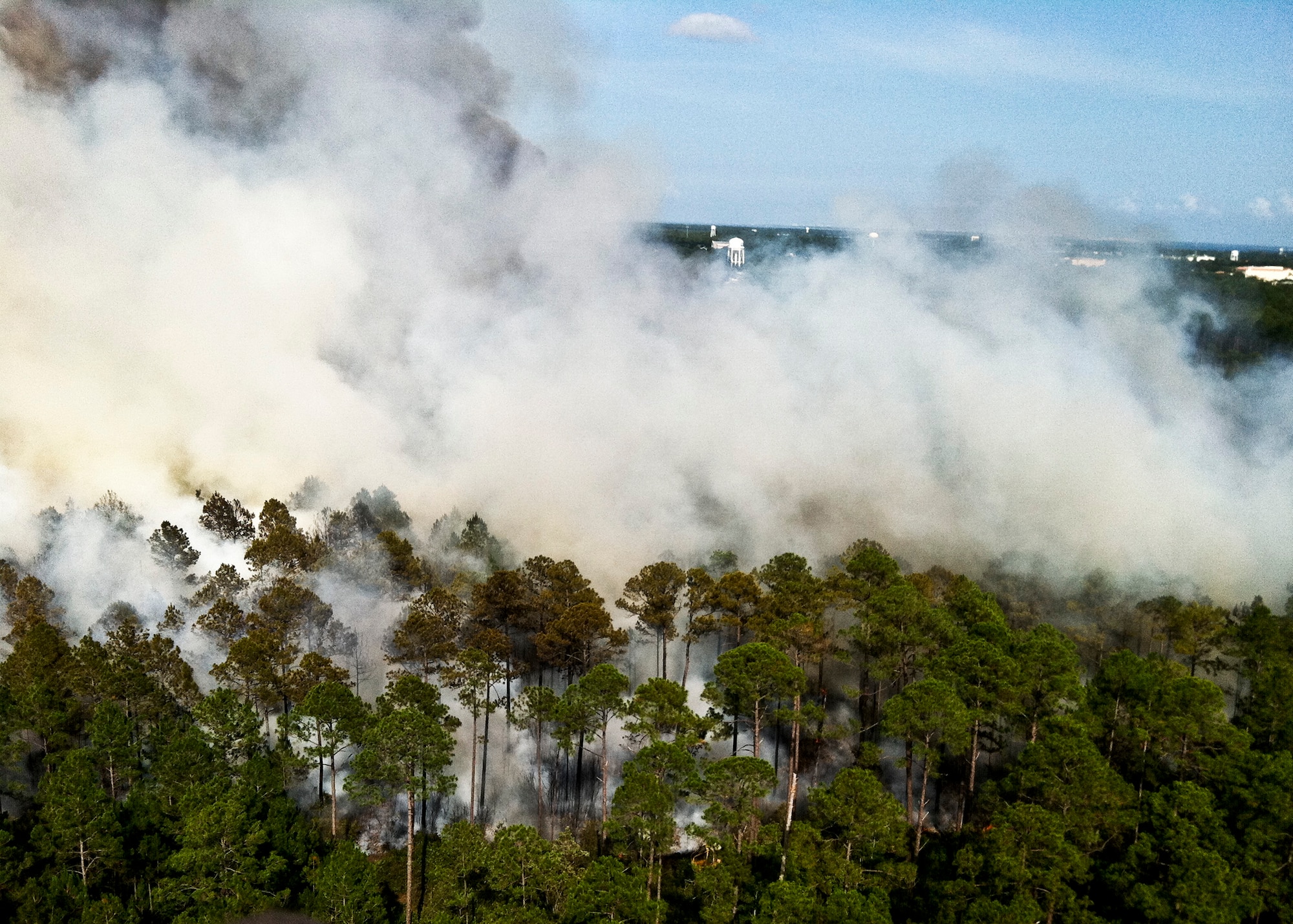 Firefighters from Jackson Guard's fire management section fly over the wildfires in a Bell 206B Jet Ranger helicopter June 22. The helicopter can carry up to 100 gallons of water in the "Bambi" bucket and place water strategically and safely. The helicopter is contracted to support Eglin's Fire Management Program in both prescribed burning and fire suppression efforts. The wildfires burned more than 15 acres of forest and threatened homes and businesses, but due to firefighting efforts no structures were damaged.  (U.S. Air Force photo/Roger Kennedy)