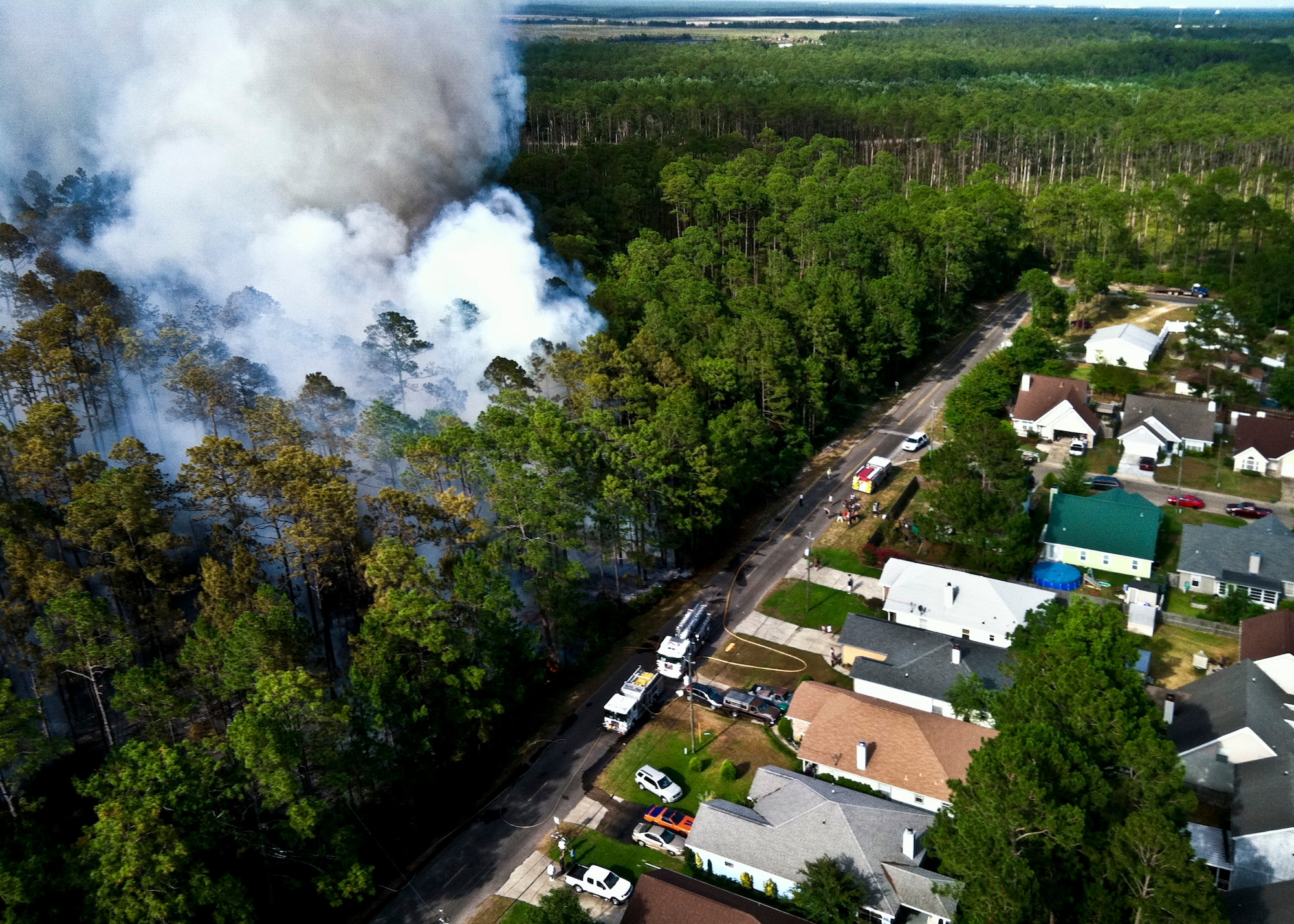 Firefighters from Jackson Guard's fire management section fly over the wildfires in a Bell 206B Jet Ranger helicopter June 22. The helicopter can carry up to 100 gallons of water in the "Bambi" bucket and place water strategically and safely. The helicopter is contracted to support Eglin's Fire Management Program in both prescribed burning and fire suppression efforts. The wildfires burned more than 15 acres of forest and threatened homes and businesses, but due to firefighting efforts no structures were damaged.  (U.S. Air Force photo/Roger Kennedy)