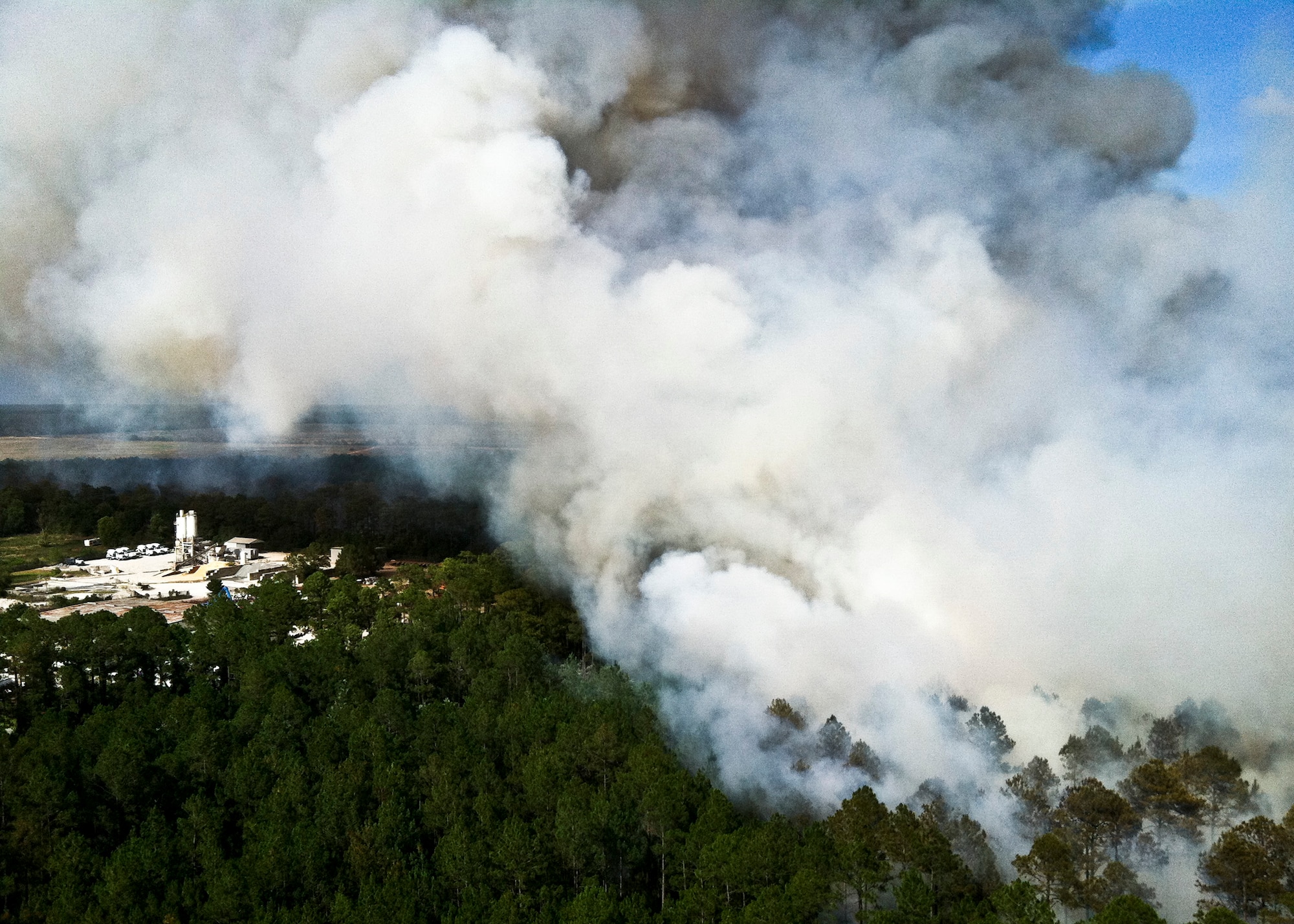 Firefighters from Jackson Guard's fire management section fly over the wildfires in a Bell 206B Jet Ranger helicopter June 22. The helicopter can carry up to 100 gallons of water in the "Bambi" bucket and place water strategically and safely. The helicopter is contracted to support Eglin's Fire Management Program in both prescribed burning and fire suppression efforts.  The wildfires burned more than 15 acres of forest and threatened homes and businesses, but due to firefighting efforts no structures were damaged.  (U.S. Air Force photo/Roger Kennedy)