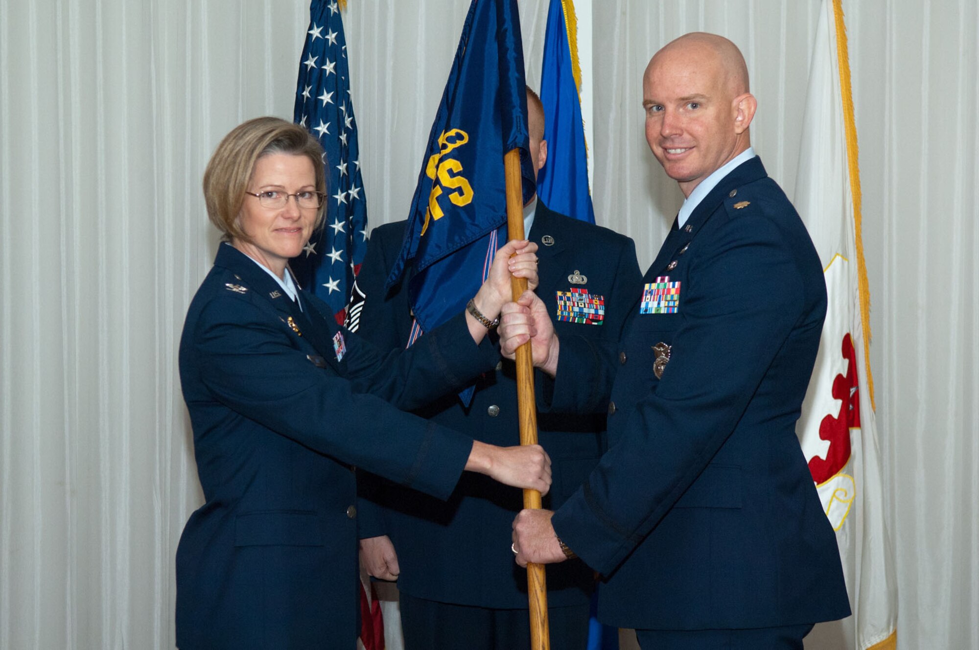 HANSCOM AIR FORCE BASE, Mass. – Col. Stacy L. Yike (left), 66th Air Base Group commander, passes the guidon to Maj. Derrick J. Weyand during the 66th Security Forces Squadron change of command ceremony at the Minuteman Club June 15. Major Weyand assumed command from Lt. Col. Chris Echols, who is moving to Lackland AFB, Texas. (U.S. Air Force photo by Rick Berry)
