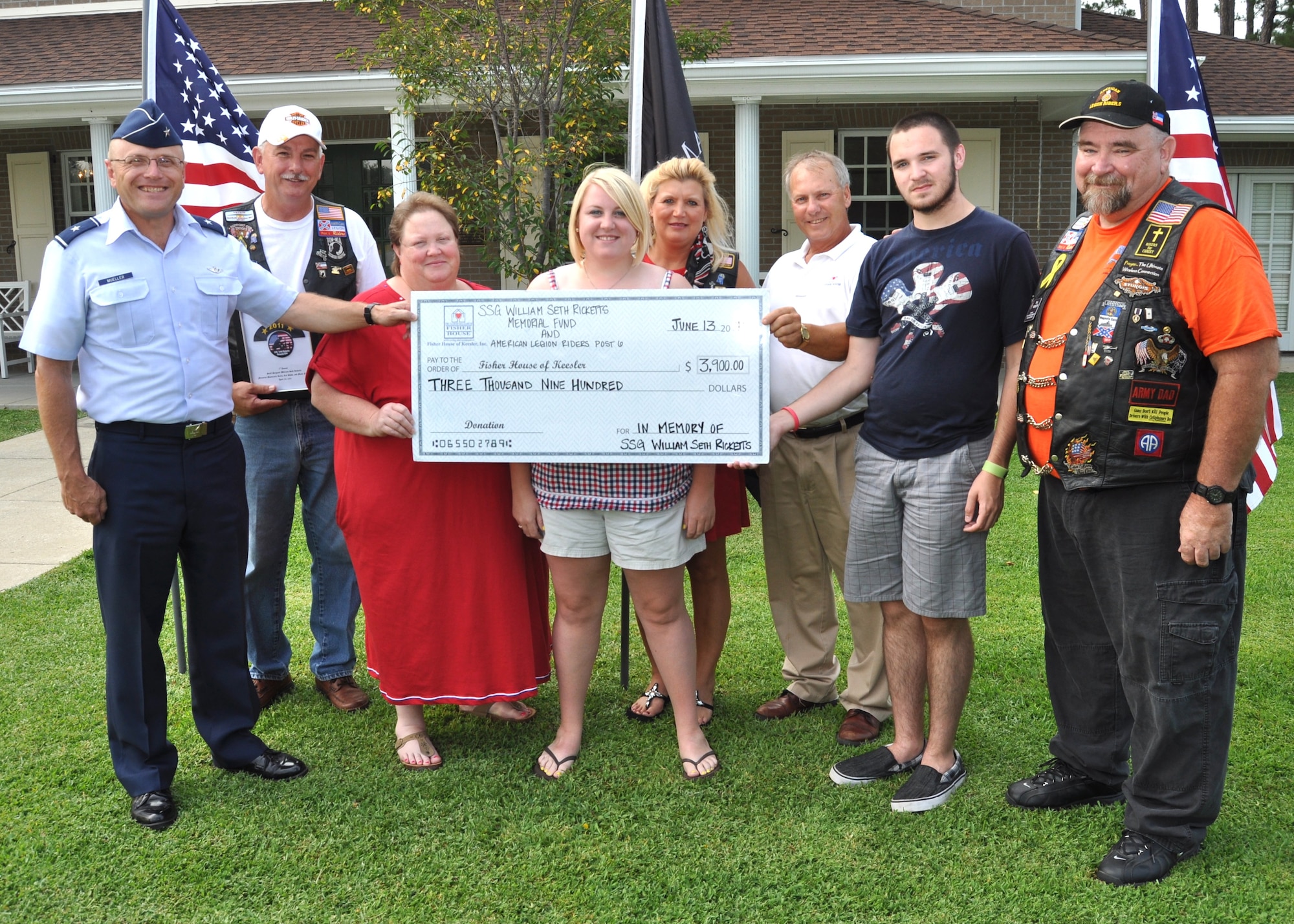 From left, holding a check representing the $3,900 donation are General Mueller, Mr. Mullins, Mrs. Ricketts, Tiffany Ricketts, Mrs. Mullins, Mr.Vetter, Ben Ricketts and Mr. Ricketts.  (U.S. Air Force photo by Steve Pivnick)