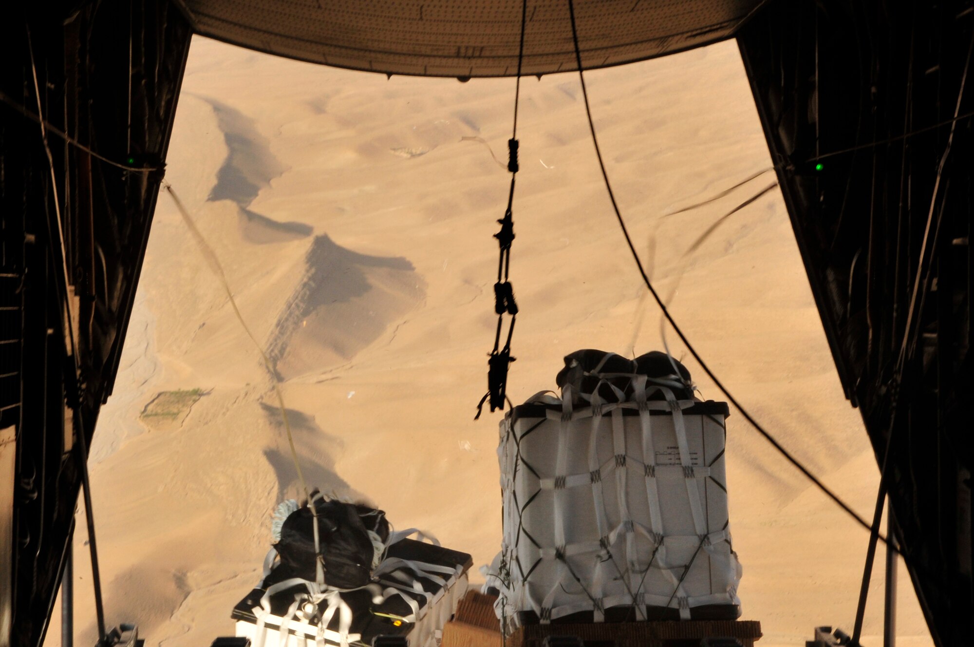 BAGRAM AIRFIELD, Afghanistan -- Pallets loaded with much-needed supplies drop out of the back of a C-130 Hercules on their way to a forward operating base in Oruzgan Province, Afghanistan, June 22. Two C-130s, one from the Alaska Air National Guard and one from the New York Air National Guard, performed the formation airdrop. Airdrops help mitigate the danger of transporting supplies via convoy. (U.S. Air Force photo by Capt. Korry Leverett)