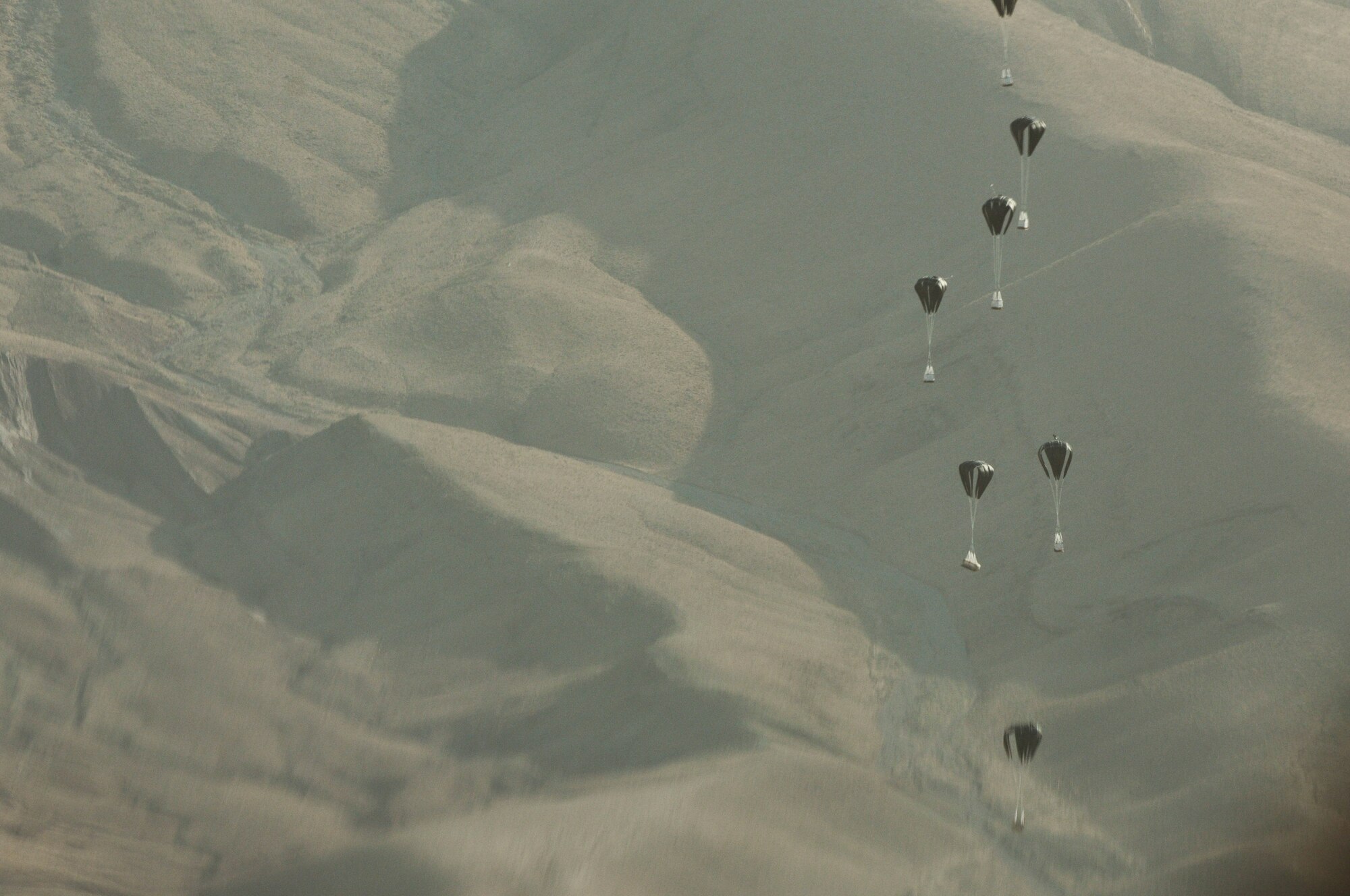BAGRAM AIRFIELD, Afghanistan -- Pallets of much-needed supplies parachute down to a forward operating base in Oruzgan Province, Afghanistan, June 22. Two C-130 Hercules aircraft, one from the Alaska Air National Guard and one from the New York Air National Guard, performed the joint airdrop. Airdrops help mitigate the danger of transporting supplies via convoy. (U.S. Air Force photo by Senior Airman Krista Rose.)